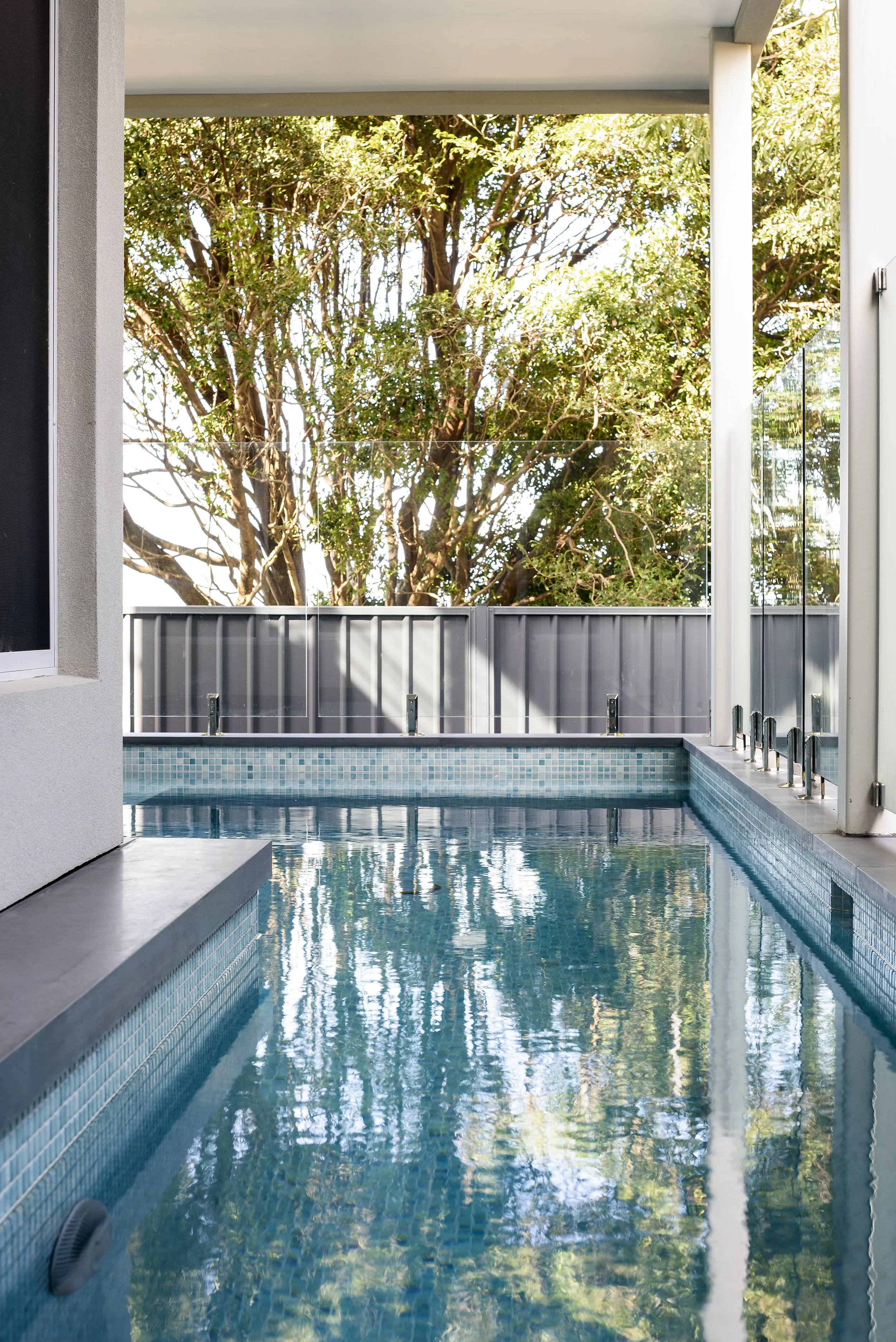 Quiet swimming pool on a balcony with trees outside.