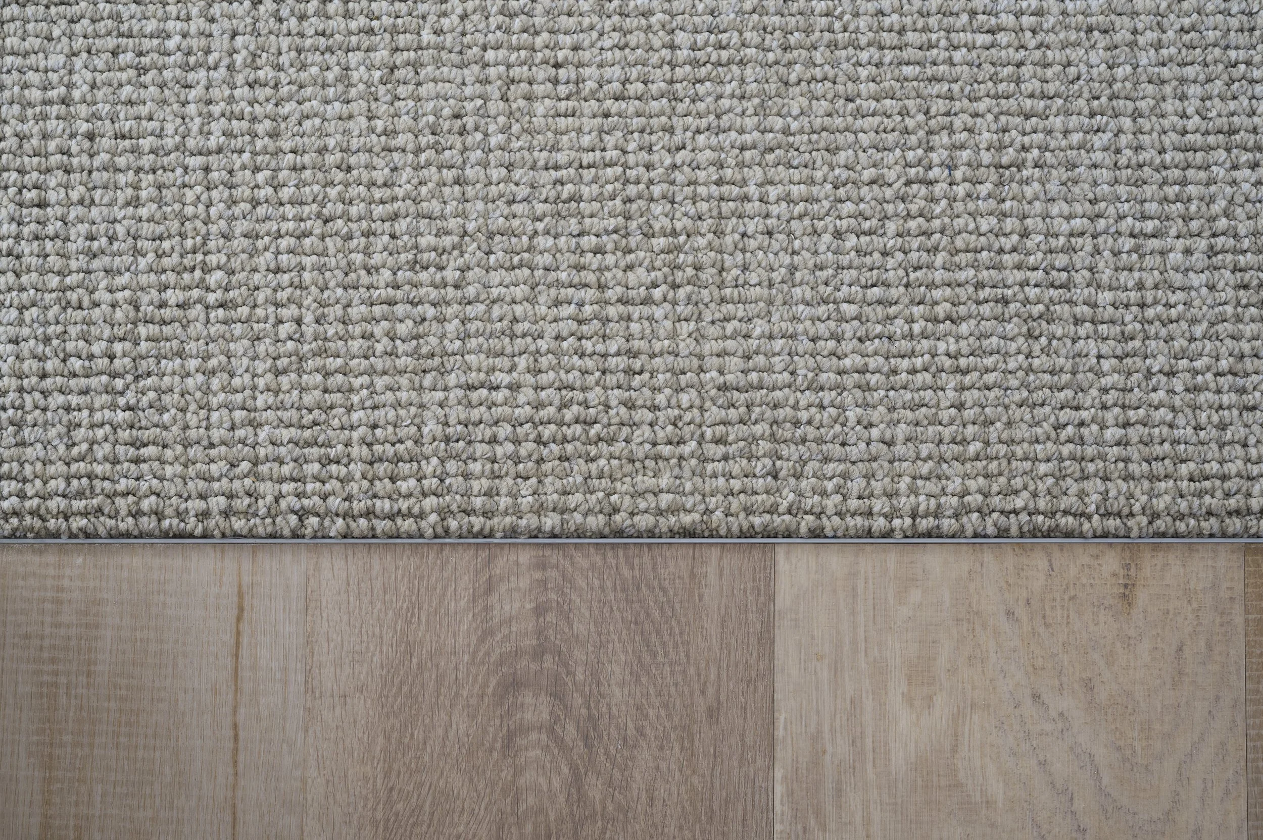 Close-up of a beige woven rug on a wooden floor.