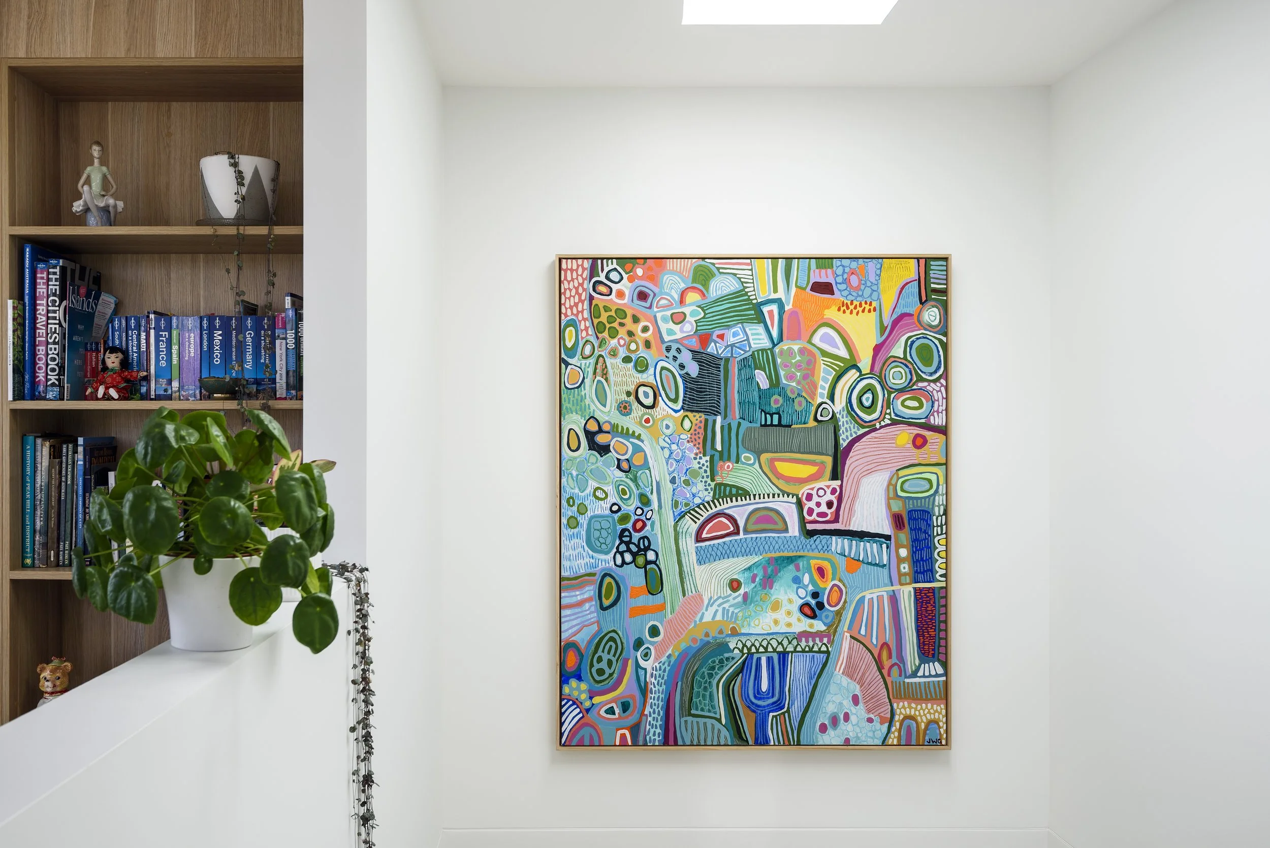 A colorful abstract painting hanging on a white wall in a well-lit room.