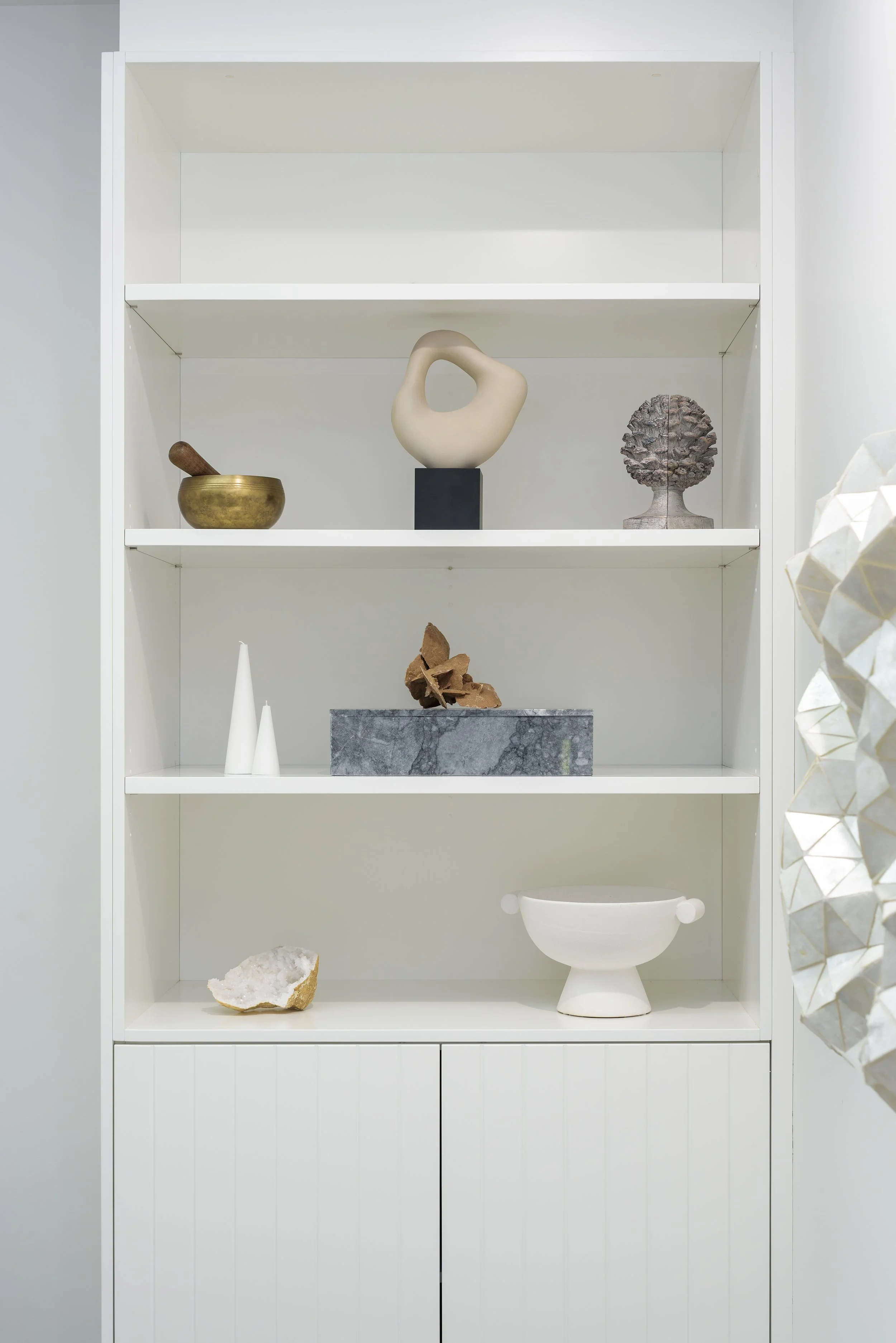 White shelf with decorative art pieces including sculptures, pottery, and rocks.