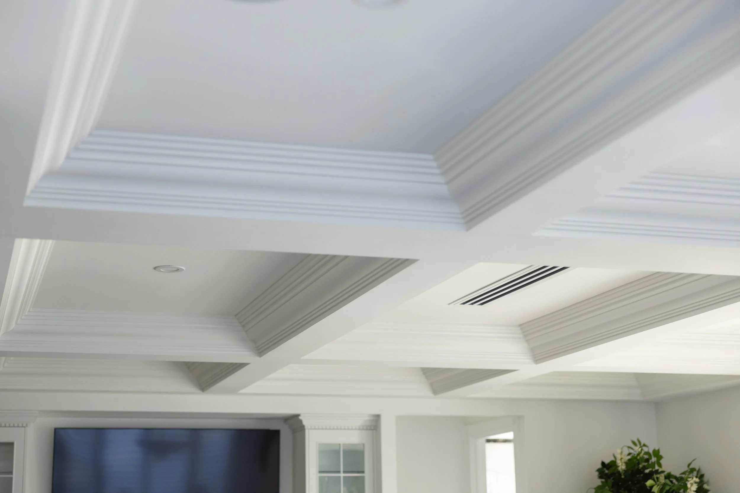 Ceiling with decorative crown molding and recessed lighting in a living room.