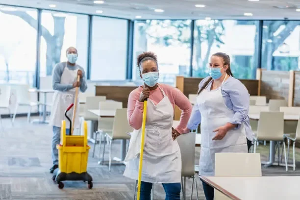 cafeteria-workers-with-broom-and-mob-wearing-mask.webp