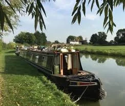 A narrowboat moored safely along a calm canal bank on the Grand Union Canal.