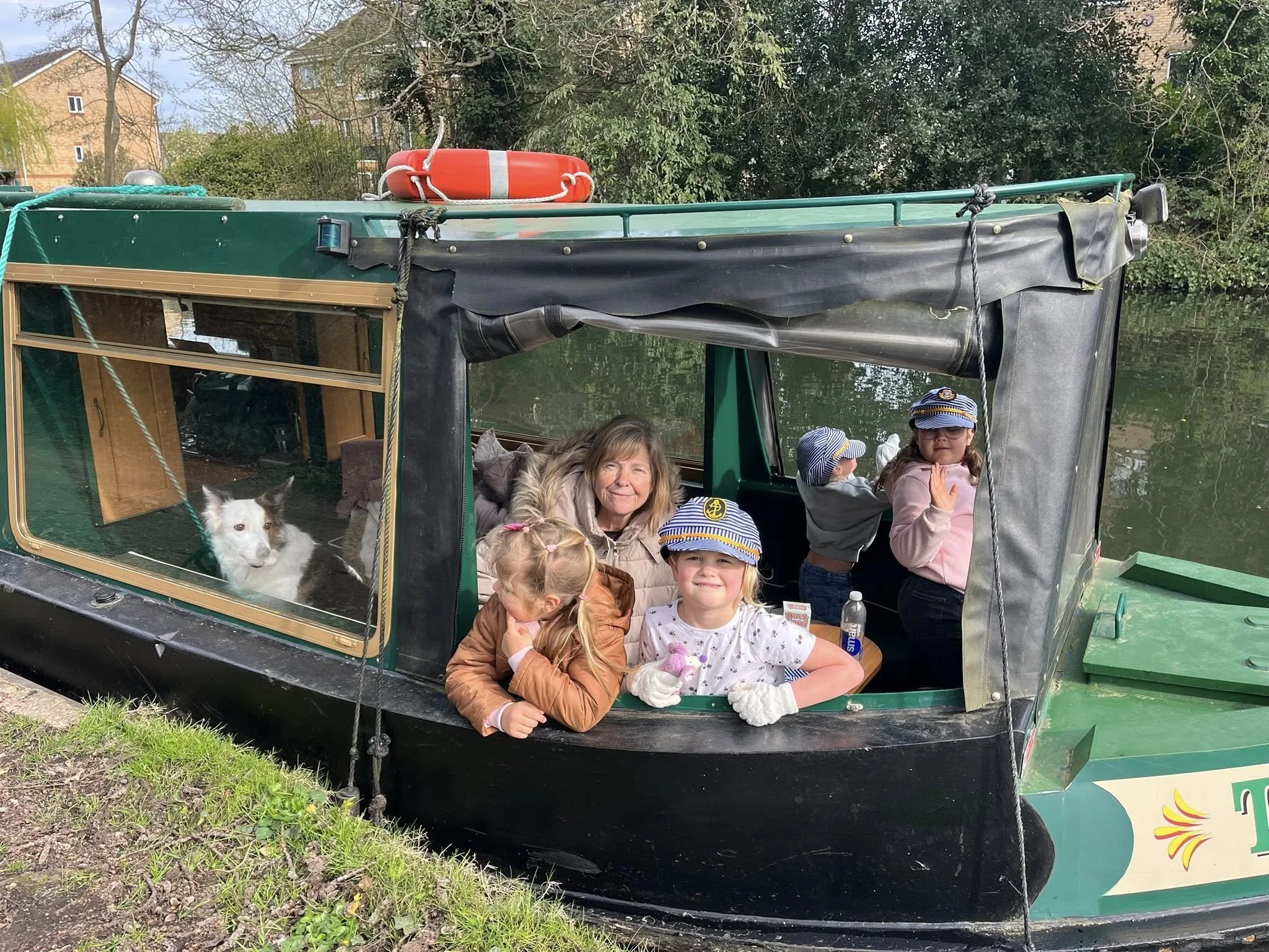 A group of children enjoying themselves on Tilly the canal boat with heir grandparent and dog