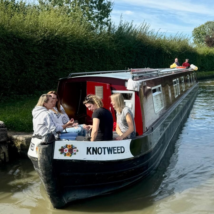 A family and small group enjoying a safe, relaxed narrowboat day hire on a calm UK canal.