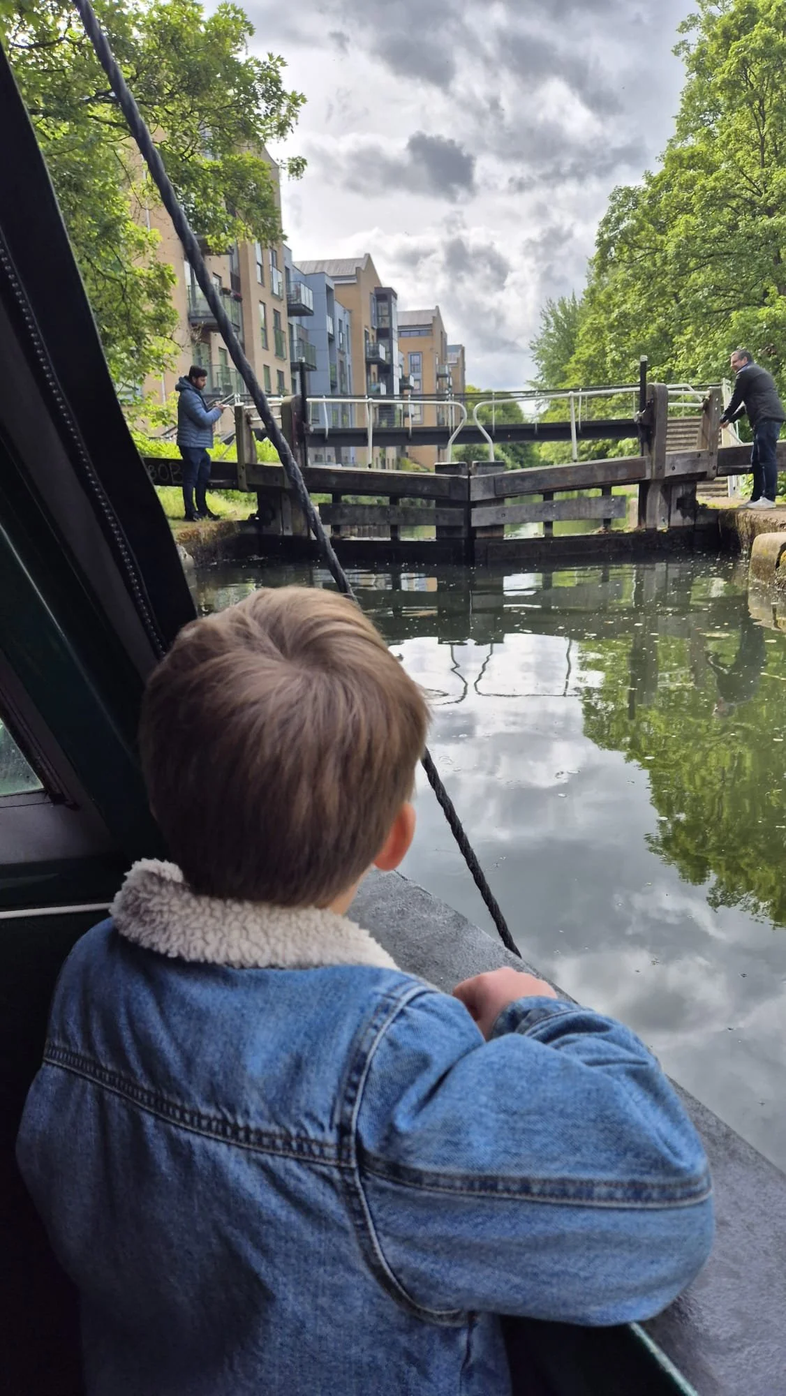 A young boy looking out of the wondow of Tilly the narrowboat, waiting for his family to open the lock
