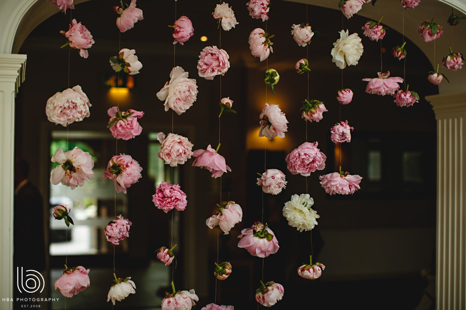 Multiple pink and white peony flowers created as a large scale floral installing hanging from the ceiling as decoration.