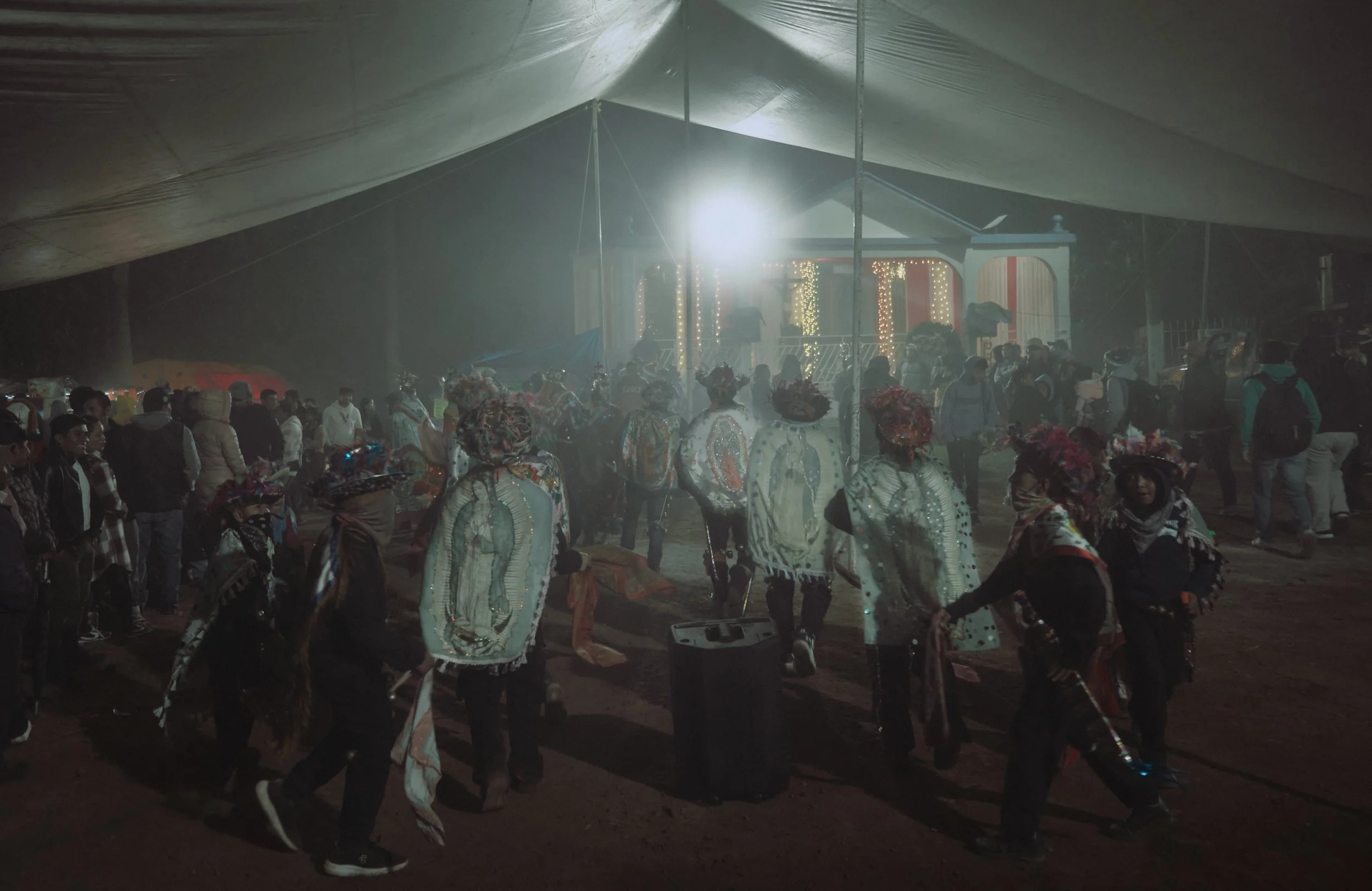 Grupo de personas participando en una celebración cultural o fiesta tradicional en la noche, con decoraciones y vestimenta colorida.
