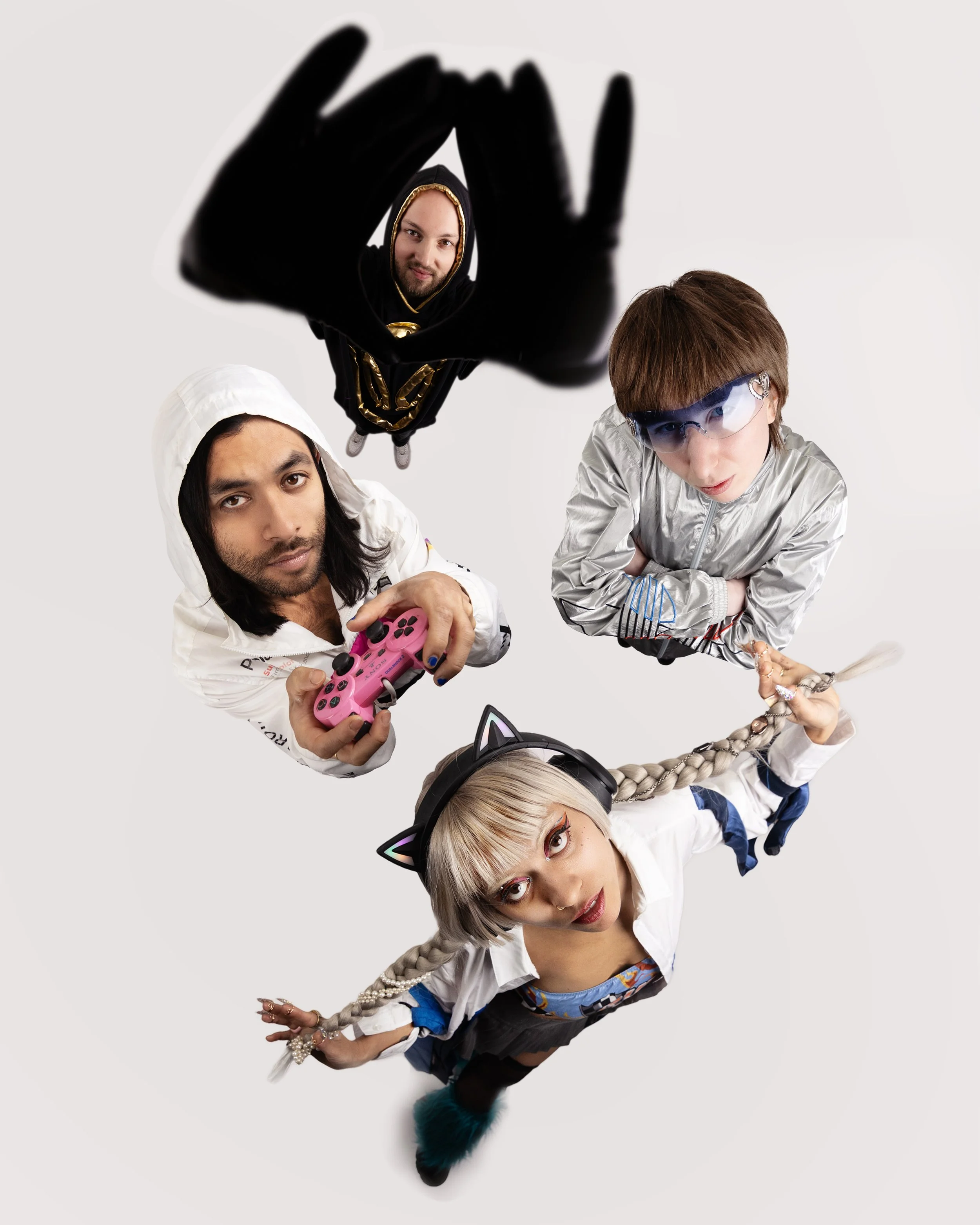 From a top-down perspective, five young adults dressed in trendy, colorful outfits pose against a plain background. They have playful expressions and are accessorized with unique clothing and gadgets. One person has cat ear headphones, another holds 