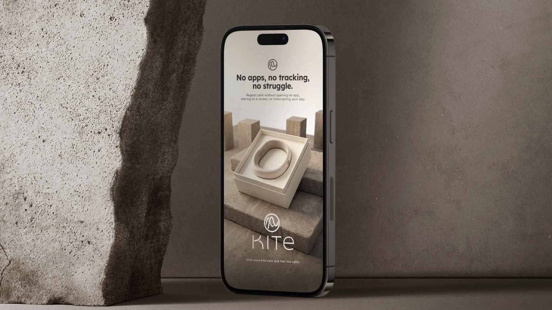 An iPhone displaying an app called 'KITE' with the tagline 'No apps, no tracking, no struggle.' The screen shows a beige wearable device in a box, set against a neutral background with abstract concrete blocks.