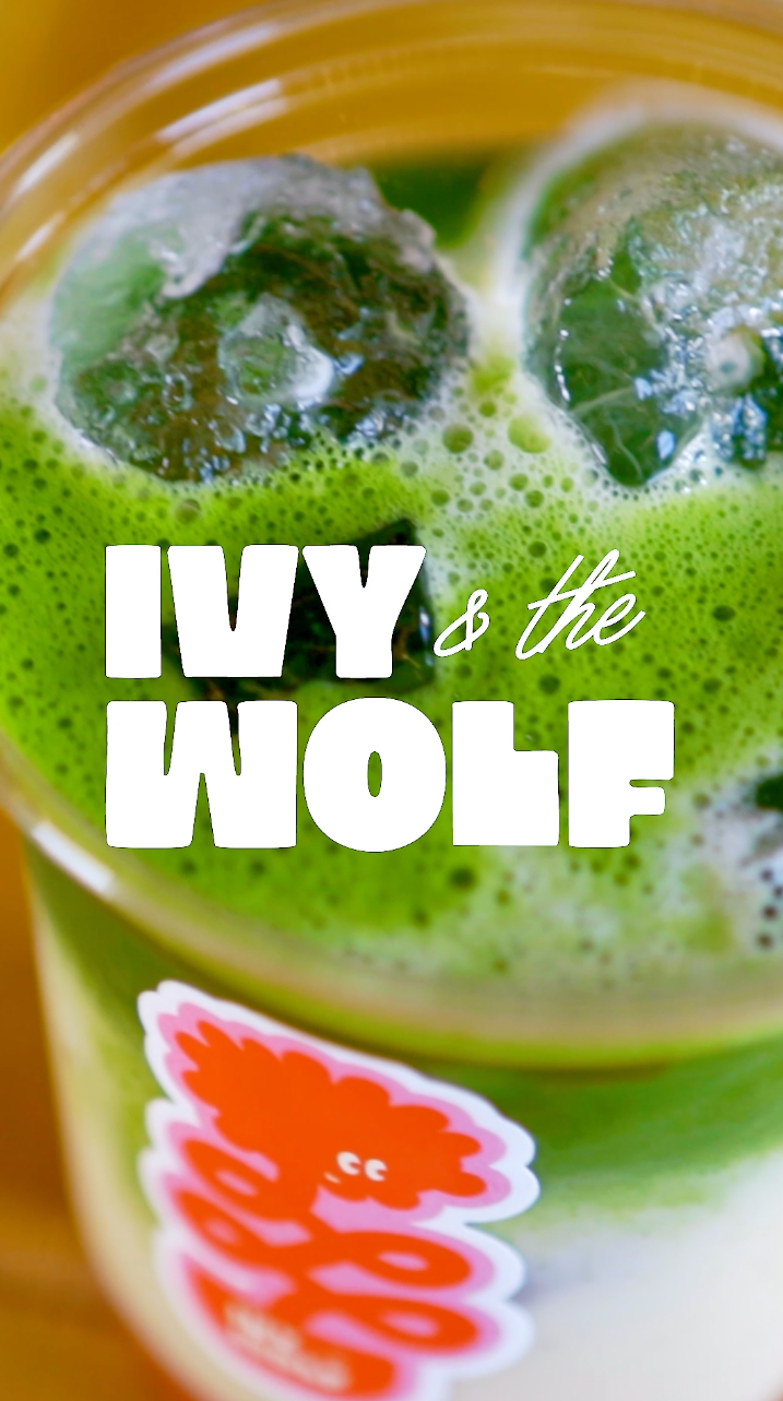 Close-up of a green beverage in a clear cup with ice cubes, with the text 'Ivy & the Wolf' overlaid.