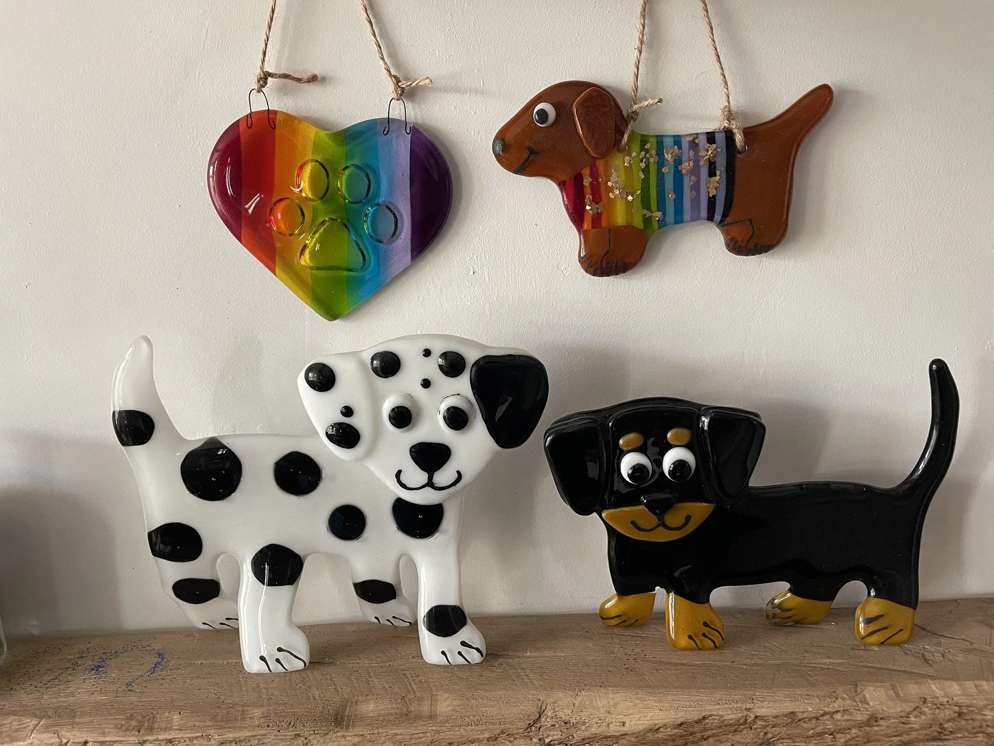 Decorative ceramic dog figurines and a rainbow-colored heart and dog-shaped plaque on a white wall.