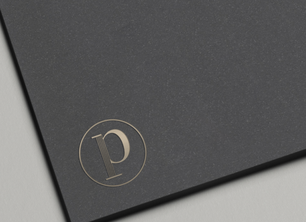 Close-up of a black textured surface with a gold circular logo containing the letter 'P'.
