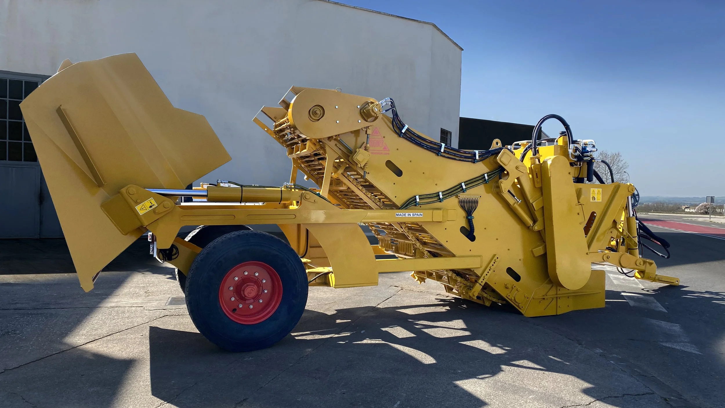 Maquinaria amarilla de gran tamaño sobre suelo de concreto, con cielo claro en el fondo.