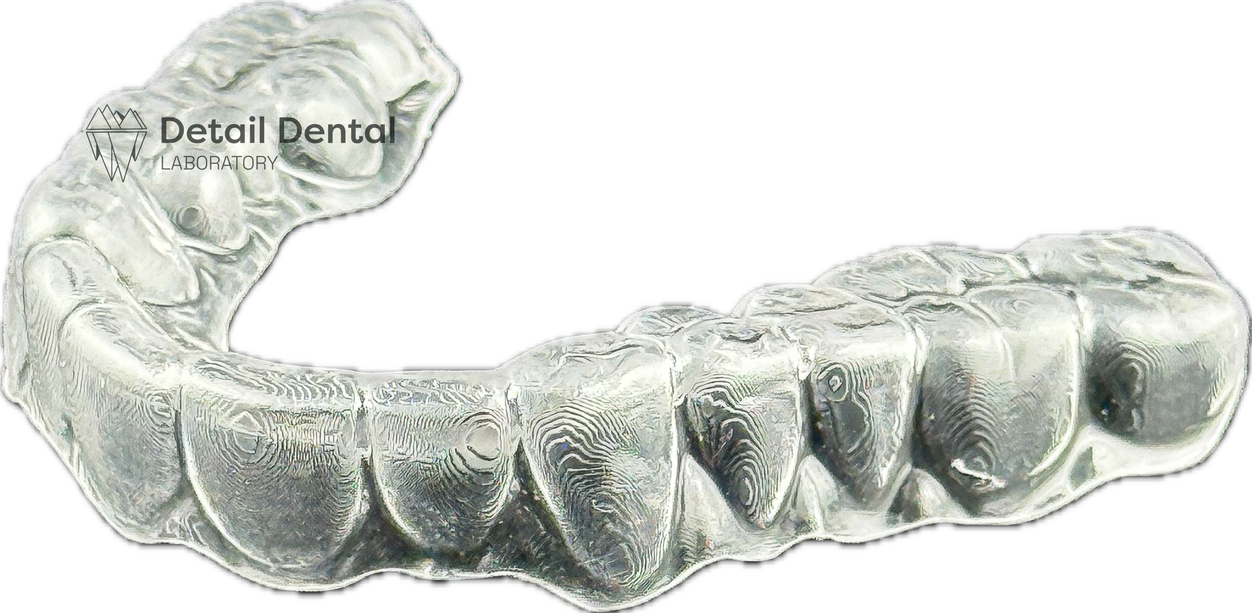 Close-up of a transparent dental aligner or retainer against a black background, with the logo and text for 'Detail Dental Laboratory' in the top left corner.
