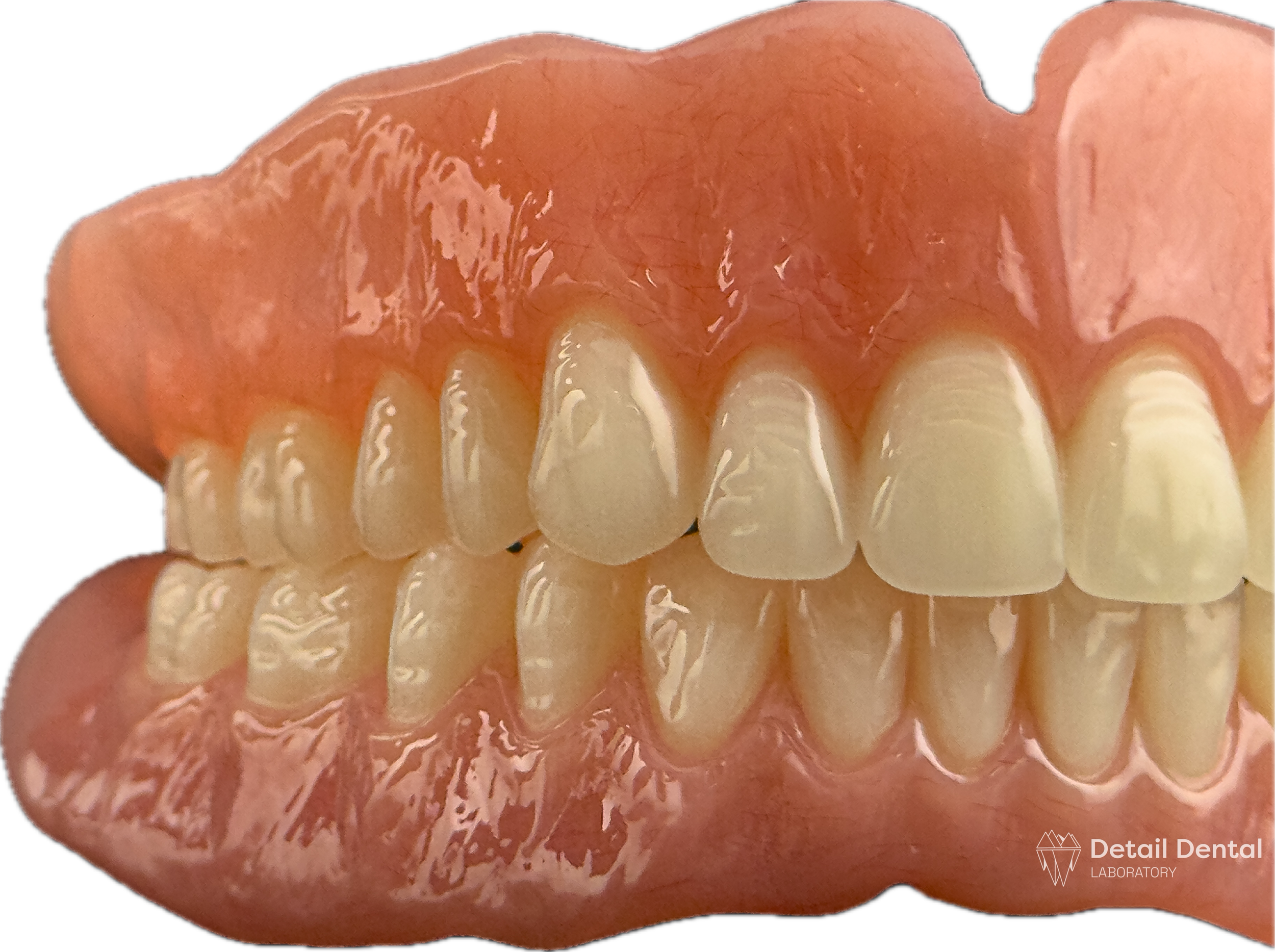 A set of artificial teeth with pink gums, displayed against a black background. The teeth are clean and well-aligned, with some variation in size. The image is from a dental laboratory, as indicated by the logo in the bottom right corner.