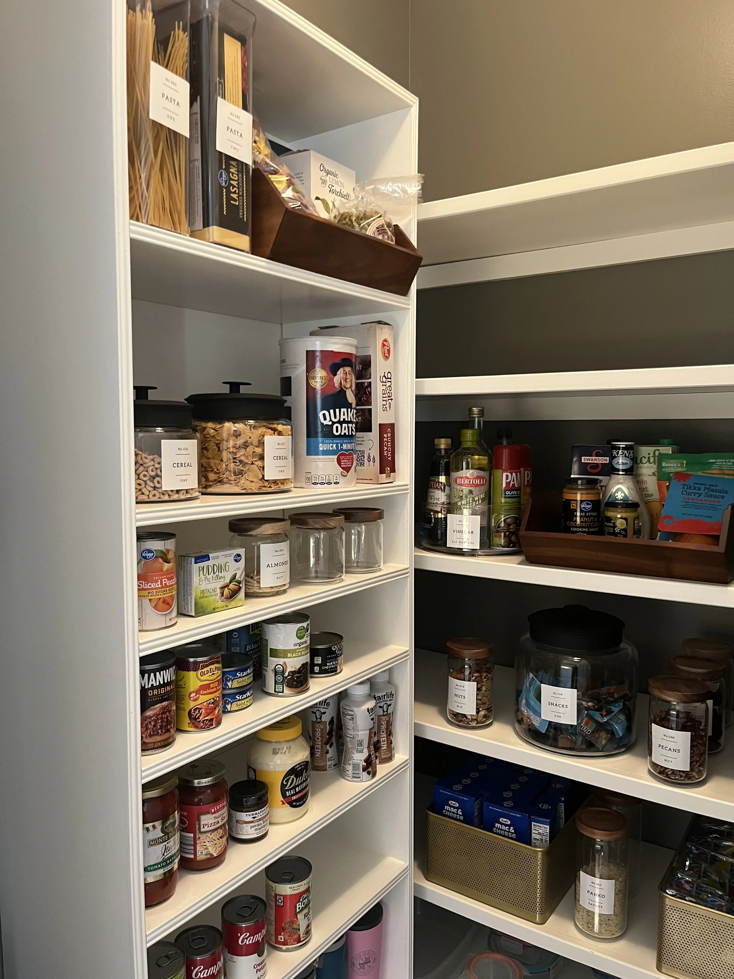 Pantry with shelves filled with canned foods, jars, snacks, pasta, cereal, and spices.