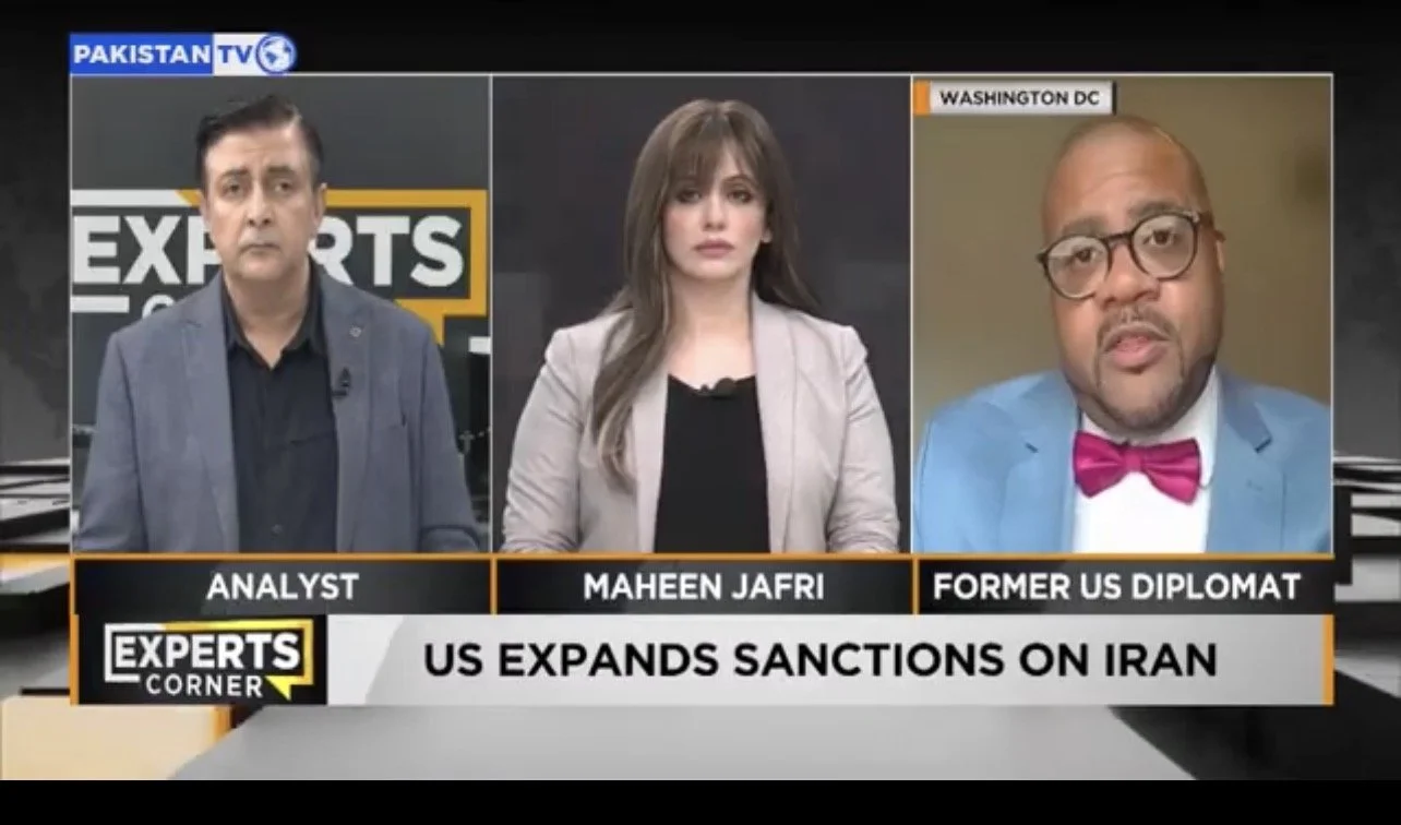Screenshot of a news panel discussing US sanctions on Iran, featuring three experts with labels 'Analyst,' 'Maheen Jafri,' and 'Former US Diplomat', with a headline 'US EXPANDS SANCTIONS ON IRAN' and 'Experts Corner' logo.