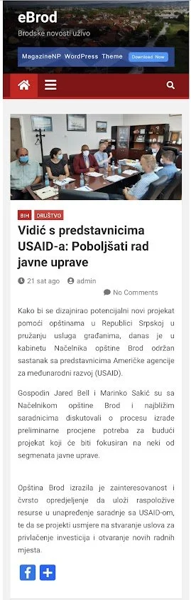 A screenshot of a news website with a headline about local officials in Brod discussing a project supported by USAID, featuring a photo of a meeting with several people wearing face masks around a table.