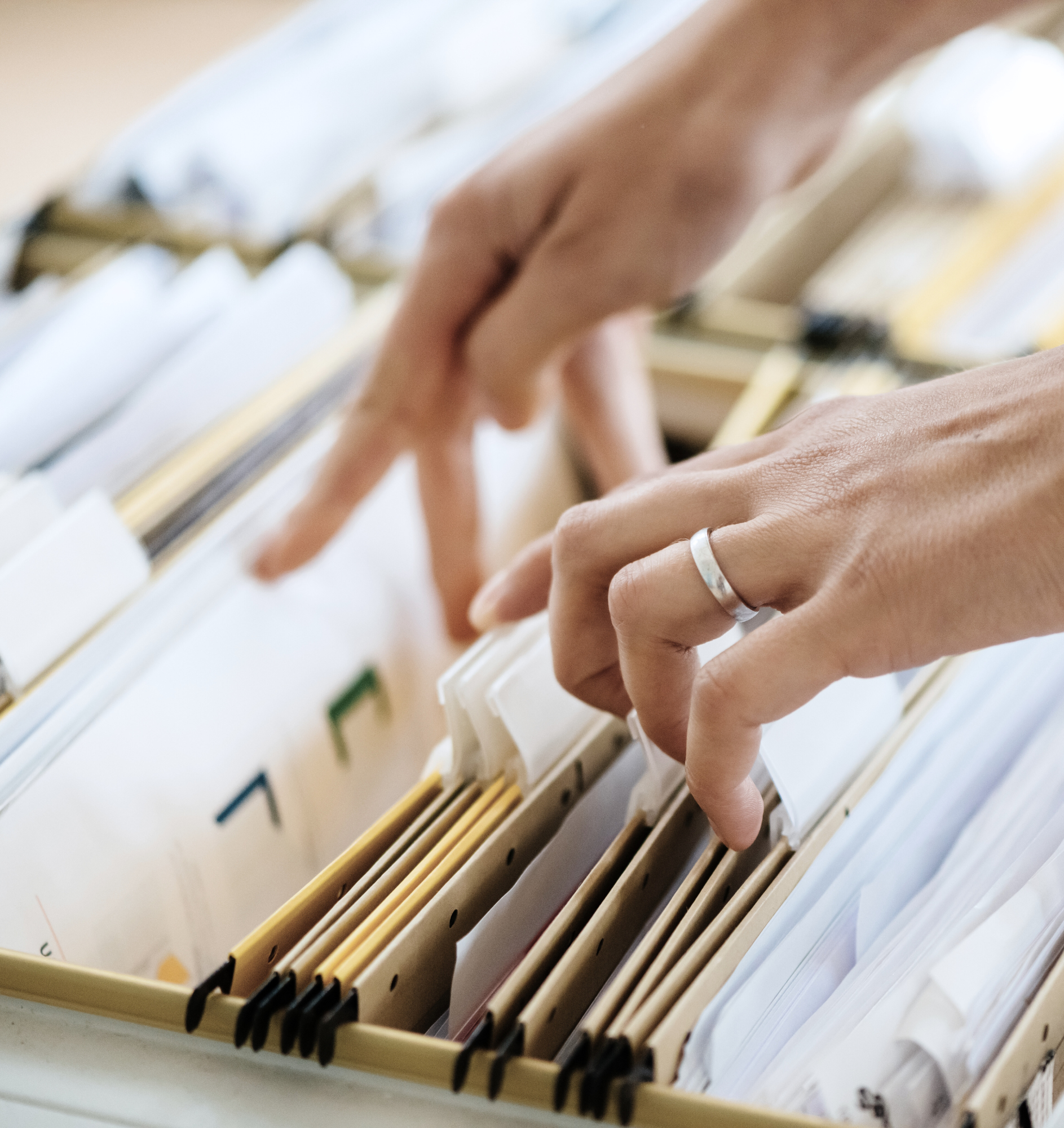 two hands flipping through a drawer of files