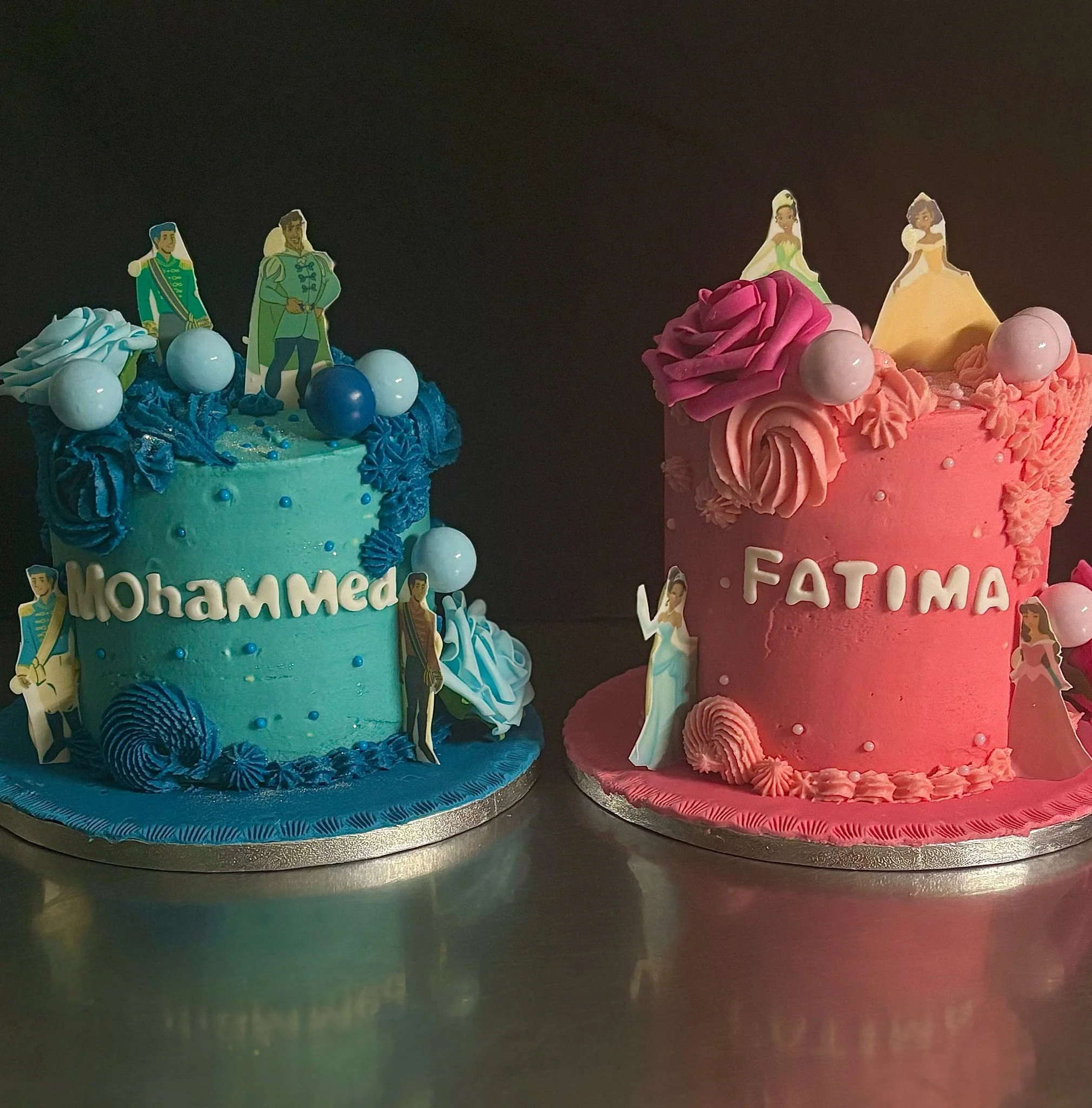 Two colorful cakes decorated with cartoon character toppers, baking decorations, and frosting details, placed on a table.