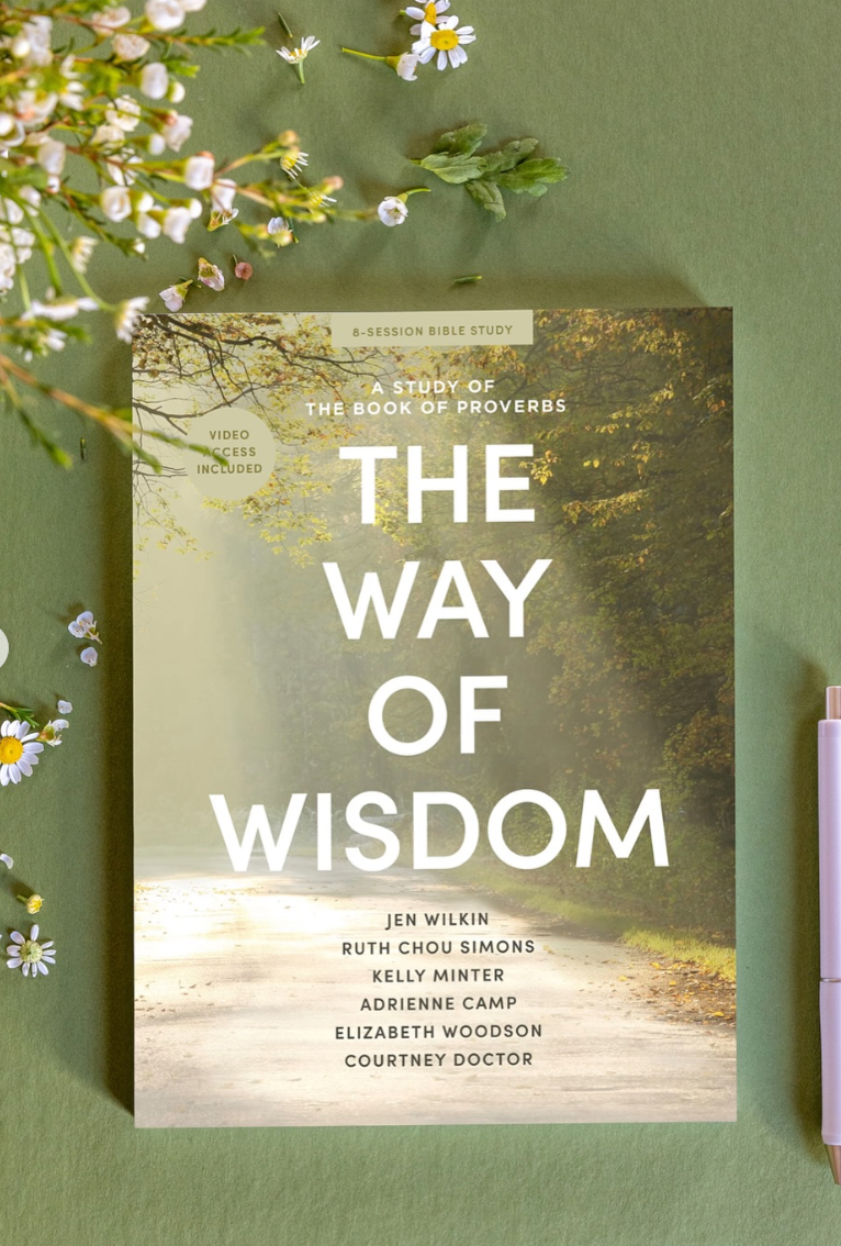 Person with hands clasped resting on open book on table.