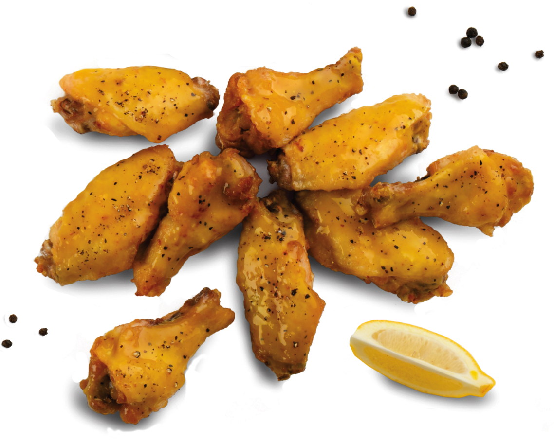 A plate of spicy buffalo chicken wings topped with melted cheese and black pepper, garnished with a lemon wedge.
