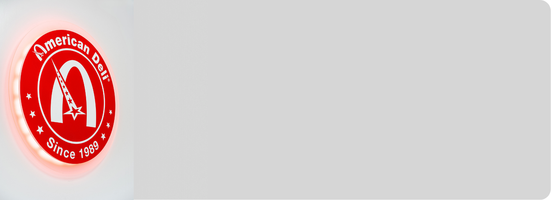 Red and white neon sign with the American Deli logo, featuring a star-shaped shooting star and the text "American Deli Since 1989."