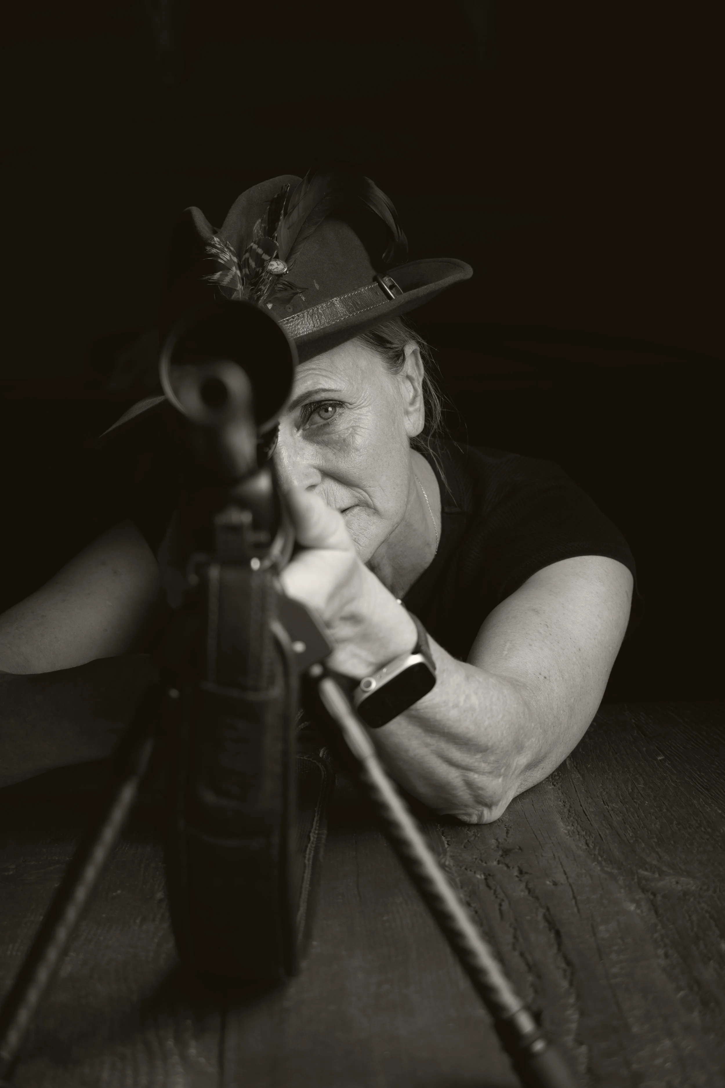 Portraitfoto einer Jägerin, die eine mit Federn beschmückte Mütze trägt, in einer schwarz-weißen Aufnahme.