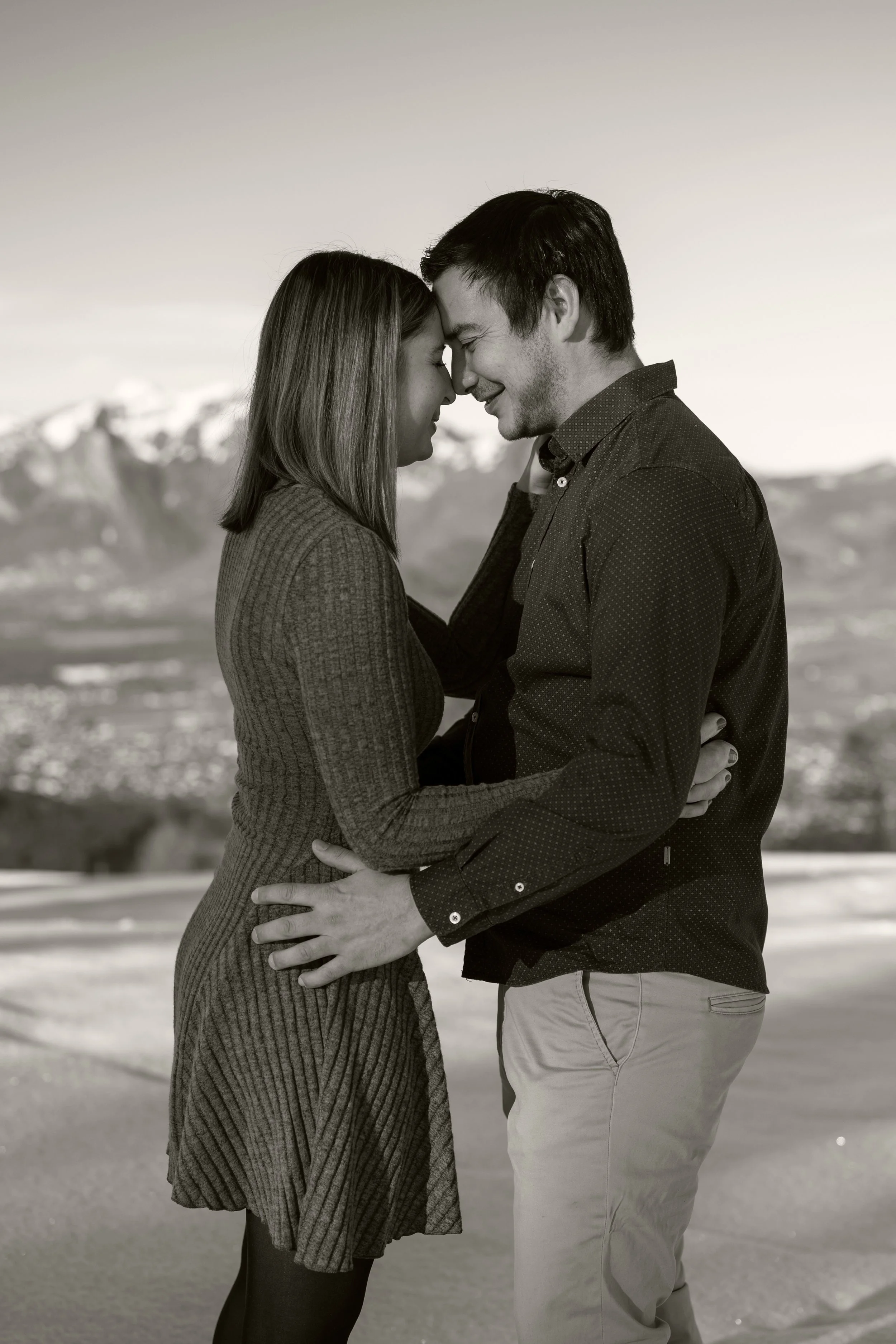 Paar steht sich gegenüber, Stirn an Stirn. Im Hintergrund eine wunderschöne Bergkulisse. Die Aufnahme ist in schwarz-weiß.