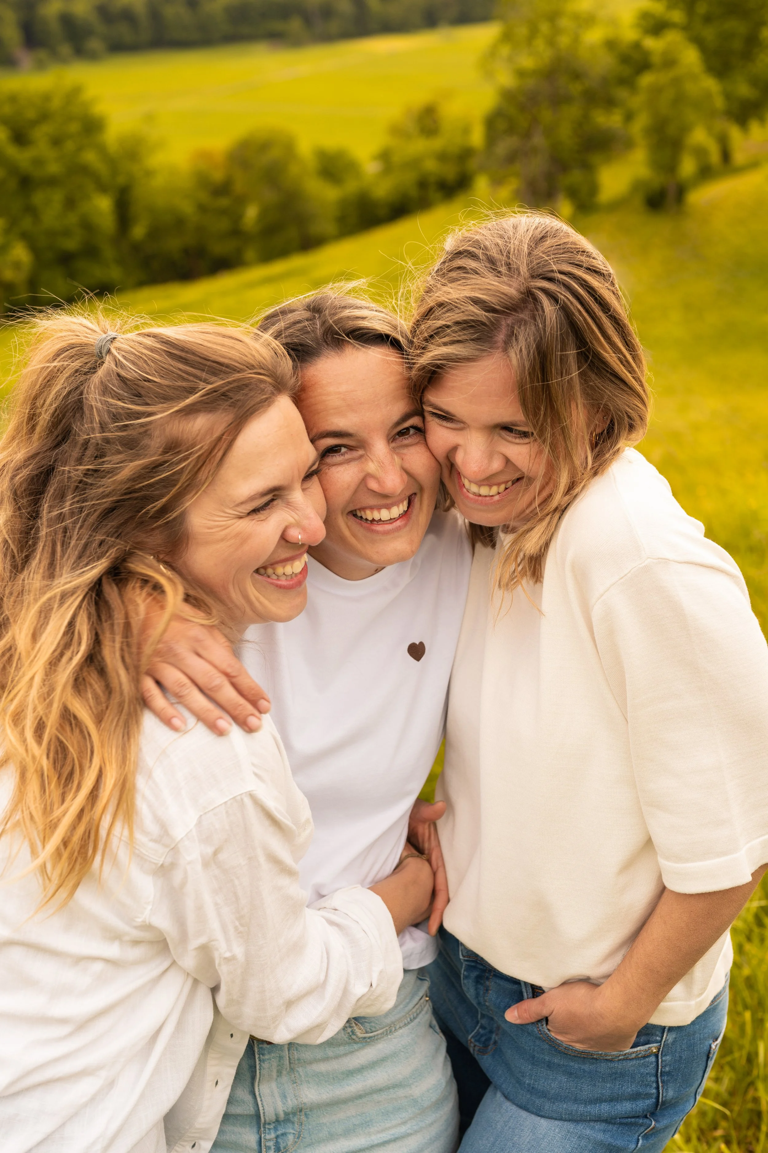 Drei Frauen stehen eng zu einander und sind einfach nur glücklich.
