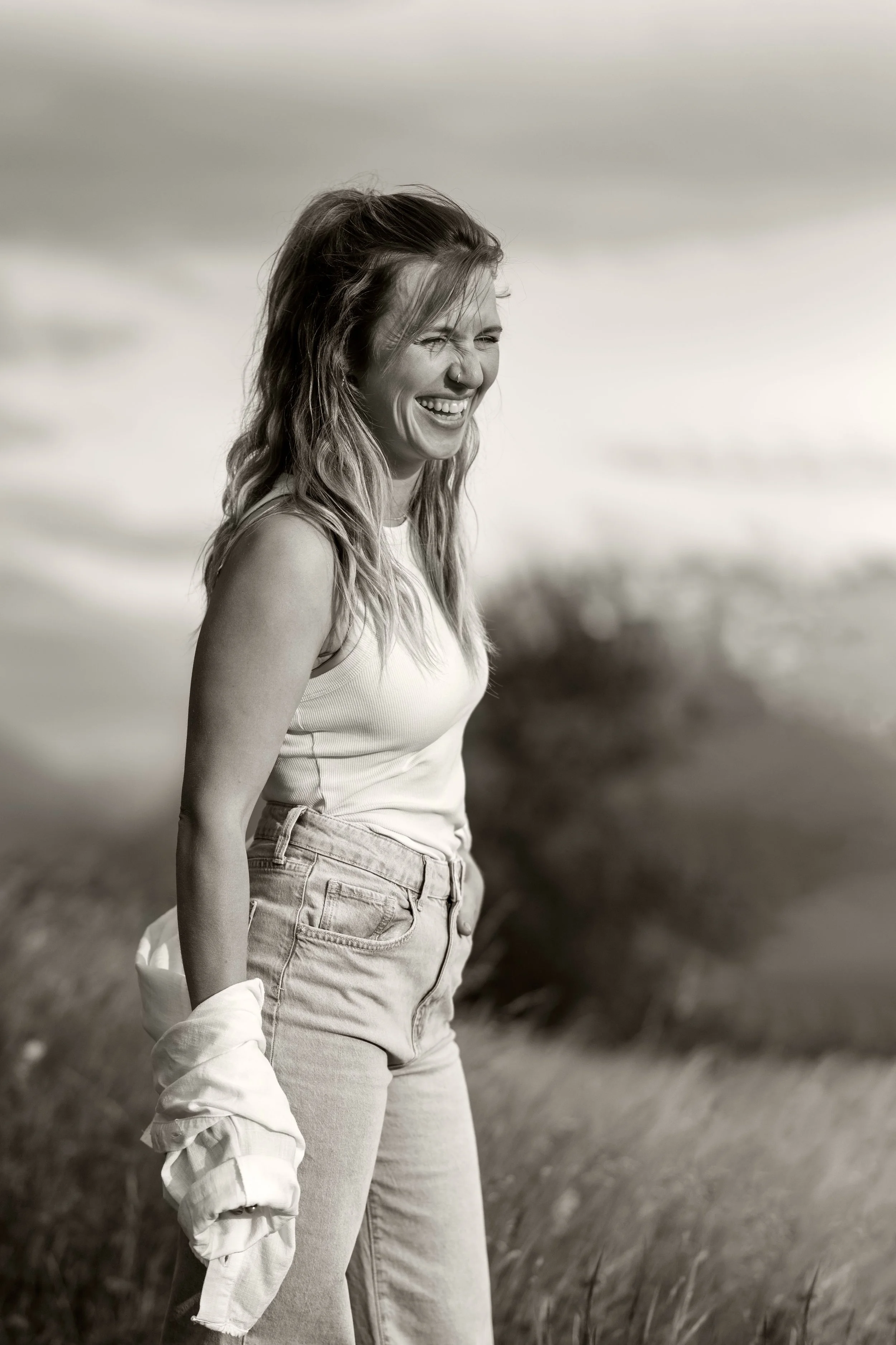 Charakterportrait einer jungen Frau in schwarz-weiß. herzhaftes Lachen, lässige Pose, sehr natürlich.