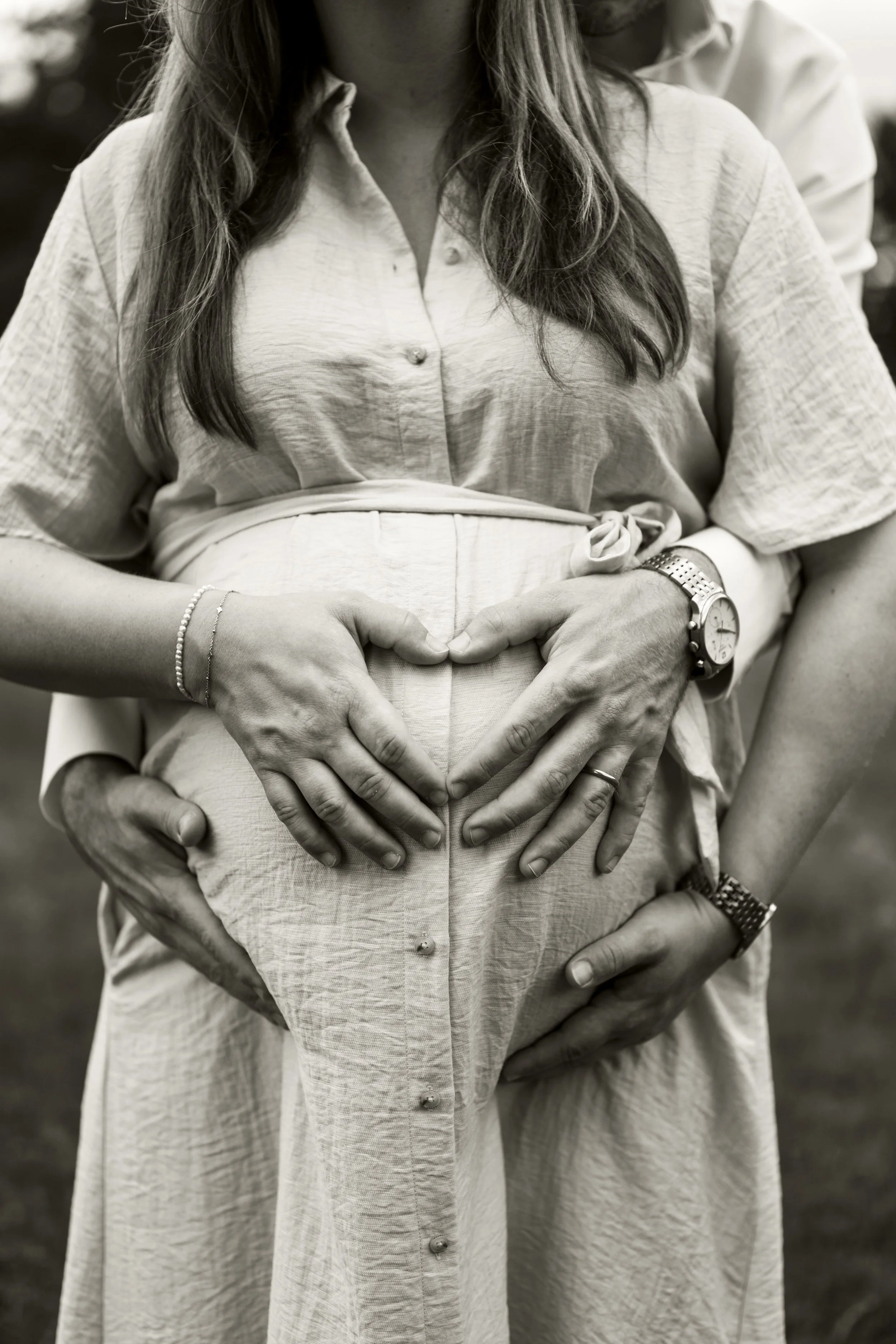 Eine Nahaufnahme eine Babybauchs. Die Hände der werdenden Eltern formen ein Herz.