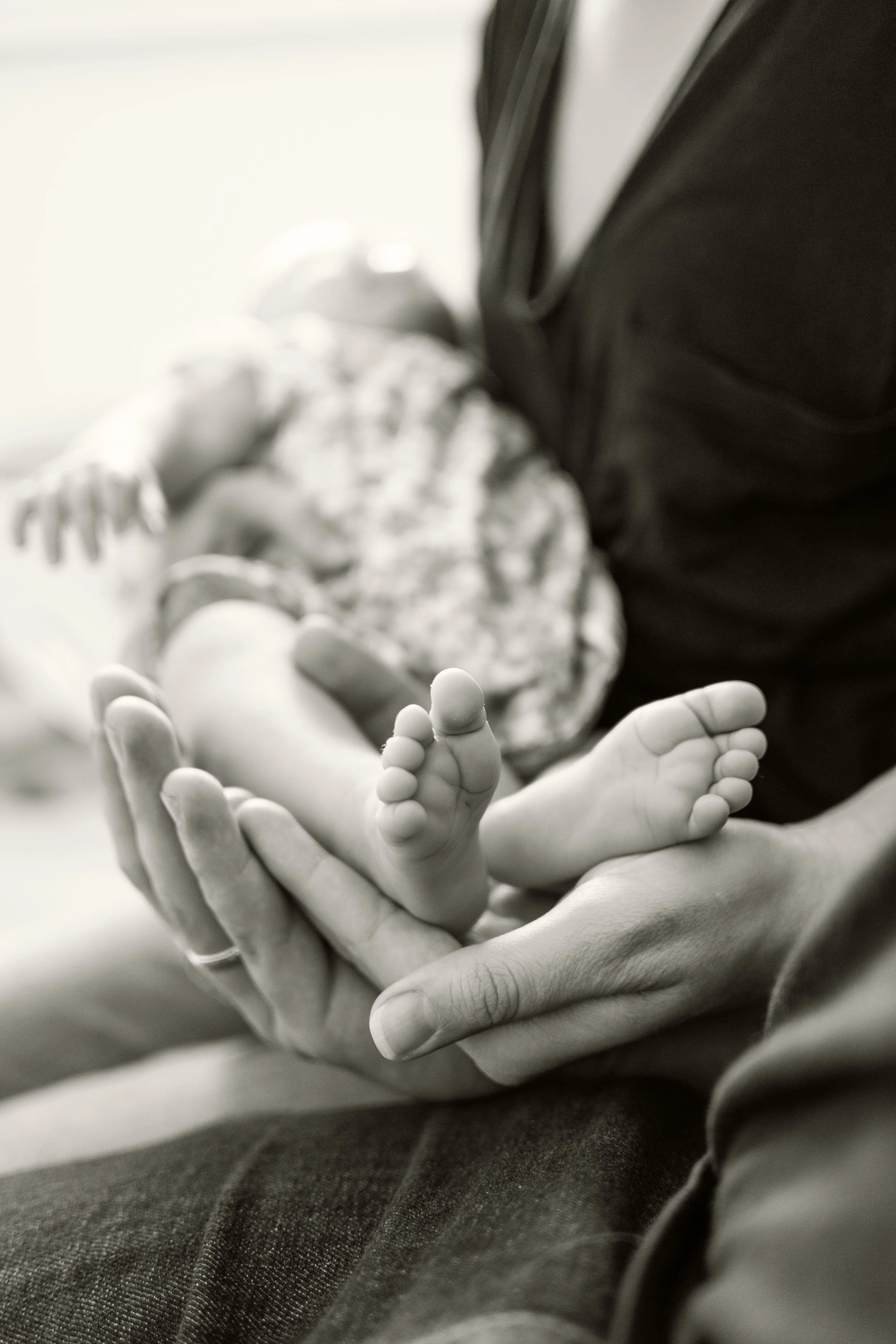 Schwarz-weiß-Aufnahme von Babyfüßen, in den Händen der Eltern.