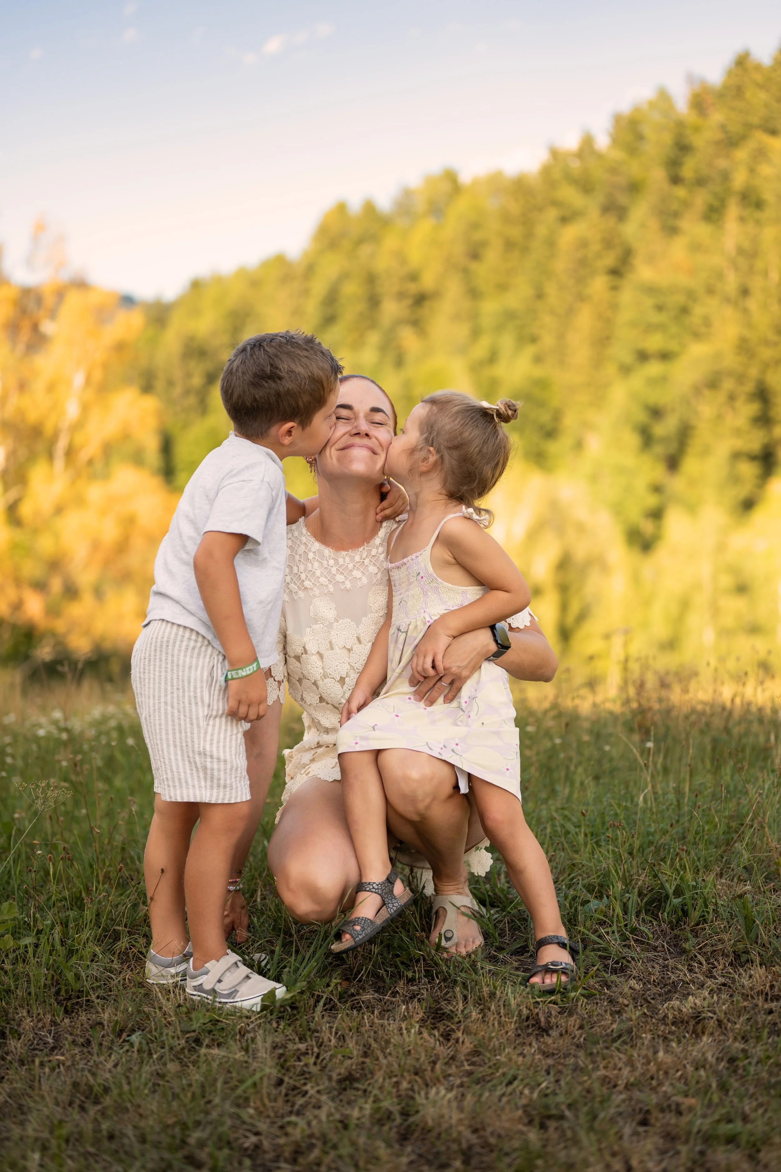 Eine Mutter wird von ihren beiden Kindern auf die Wange geküsst.