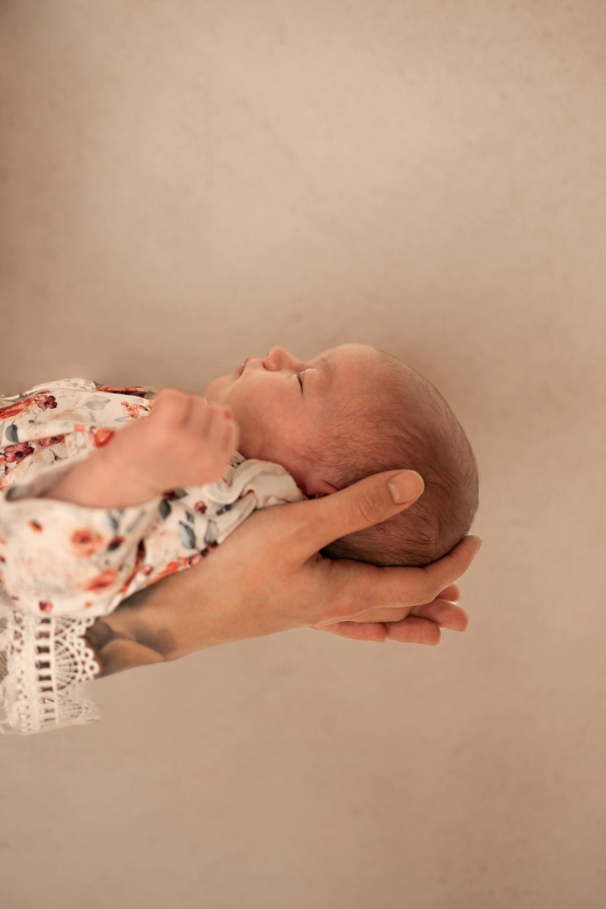 Baby liegt entspannt in den Händen der Mutter.