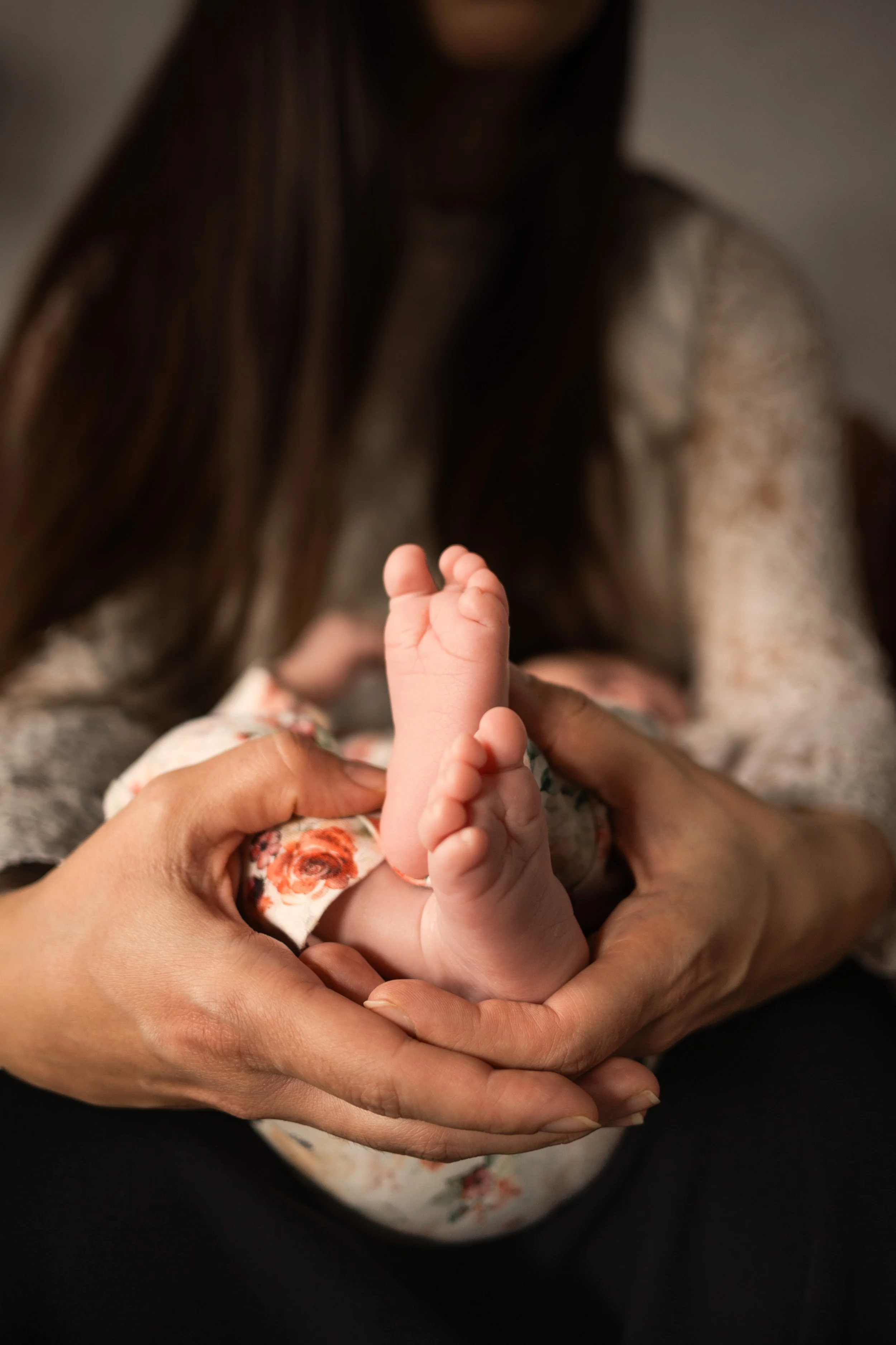 Kleine Babyfüße in den Händen der Mutter.