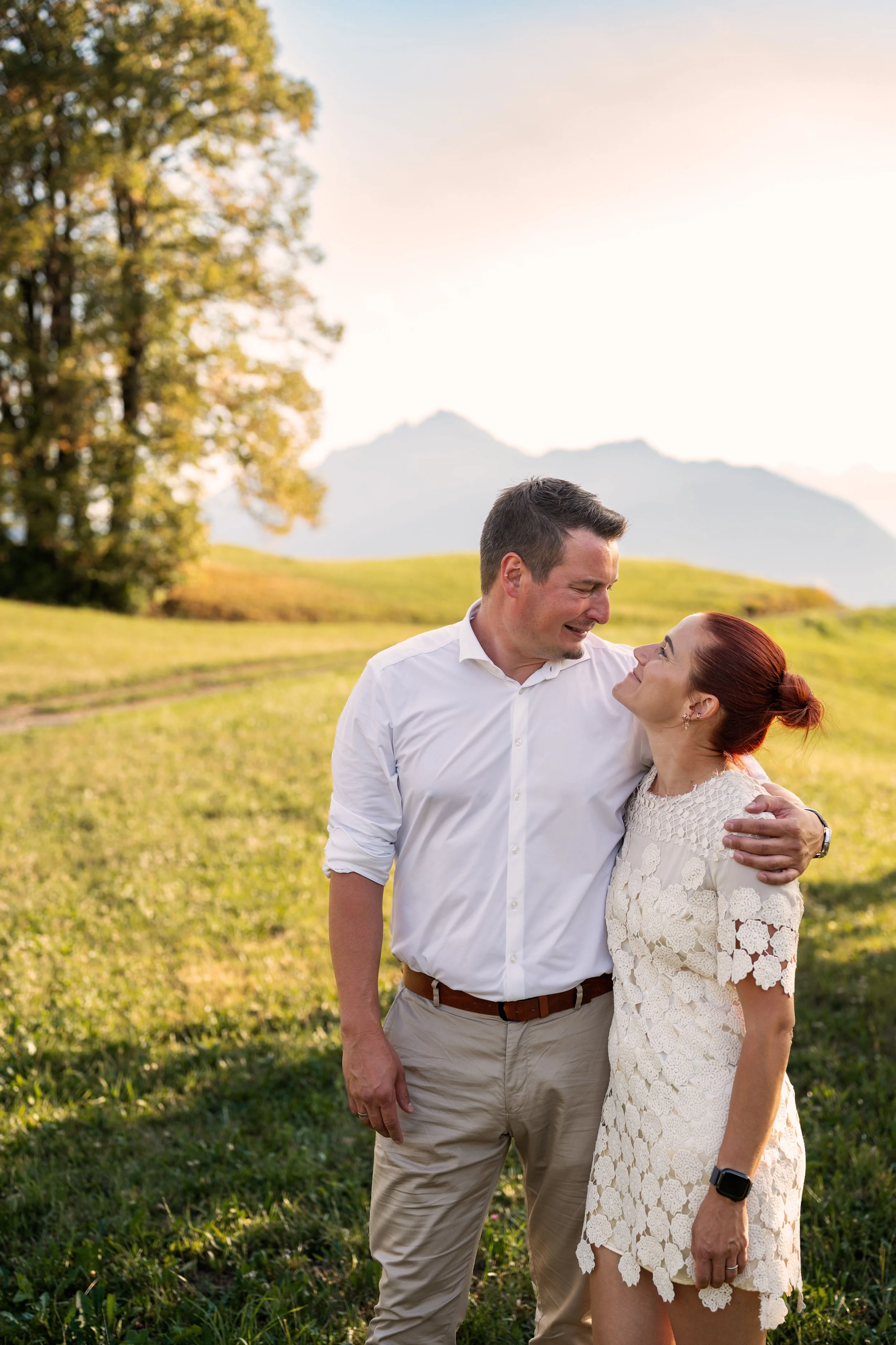 Ein Mann und eine Frau stehen nebeneinander. Sie halten sich und blicken sich lächelnd in die Augen.