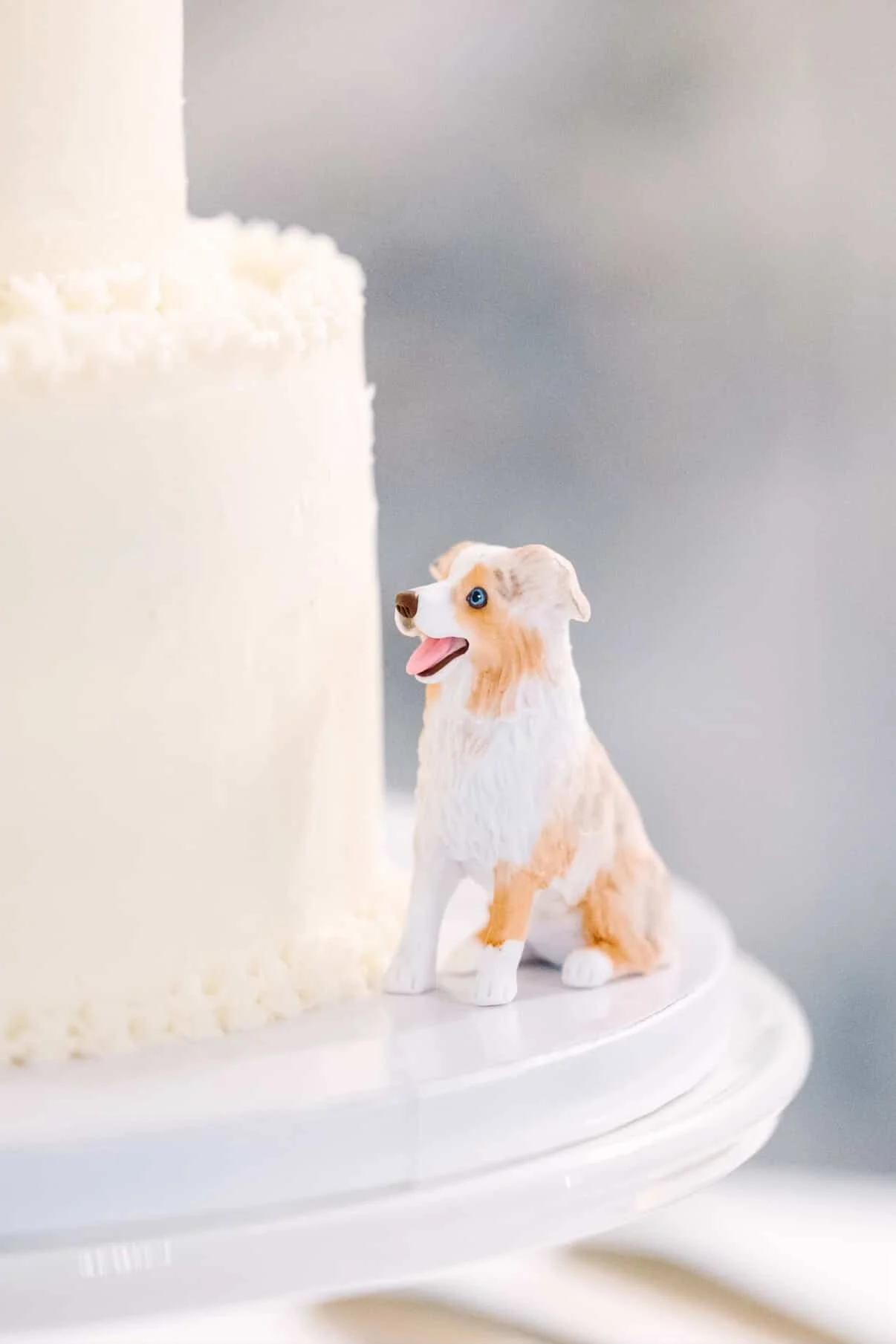A dog figurine placed near a white cake on a cake stand.