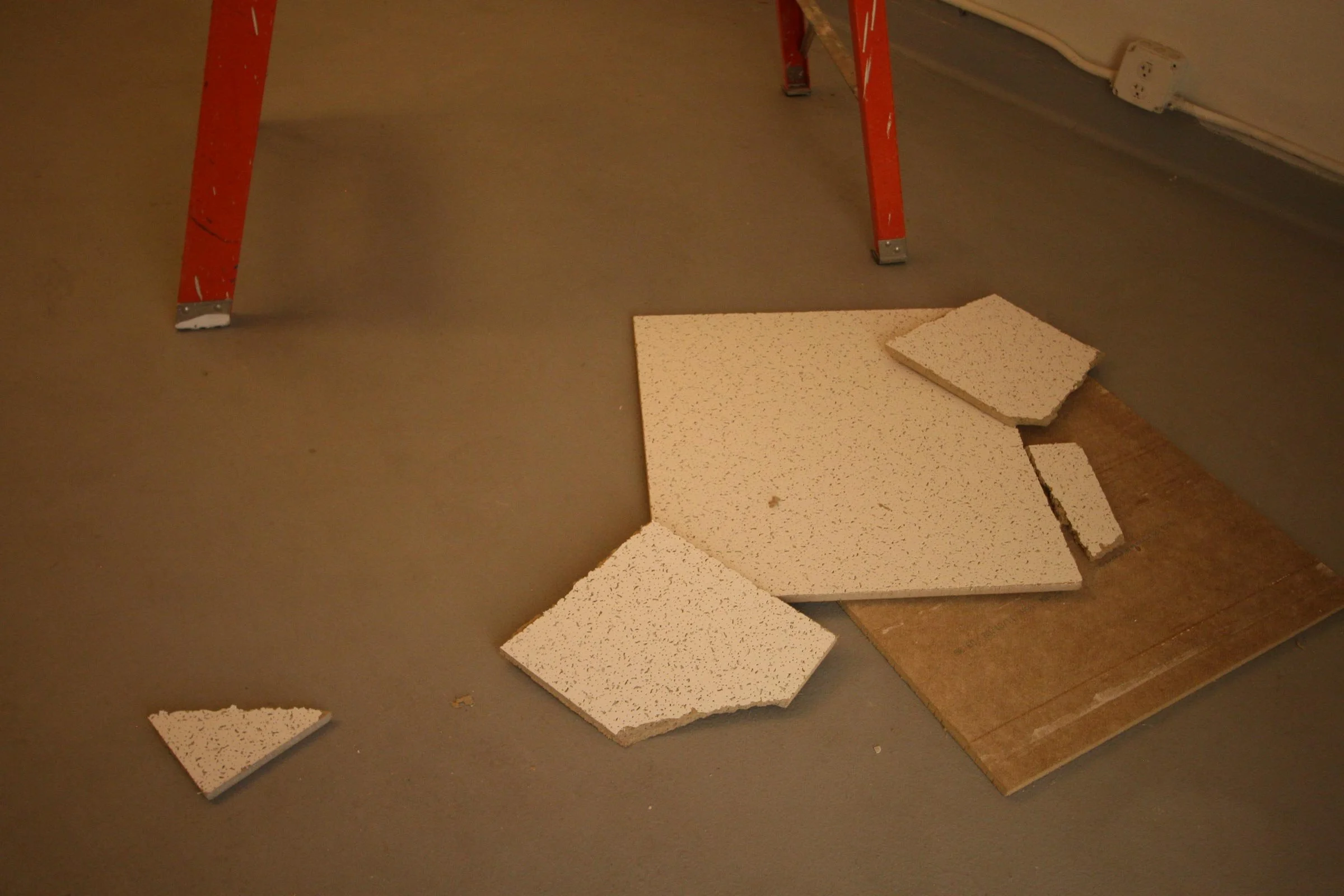Ceiling tiles lay strewn across the floor
