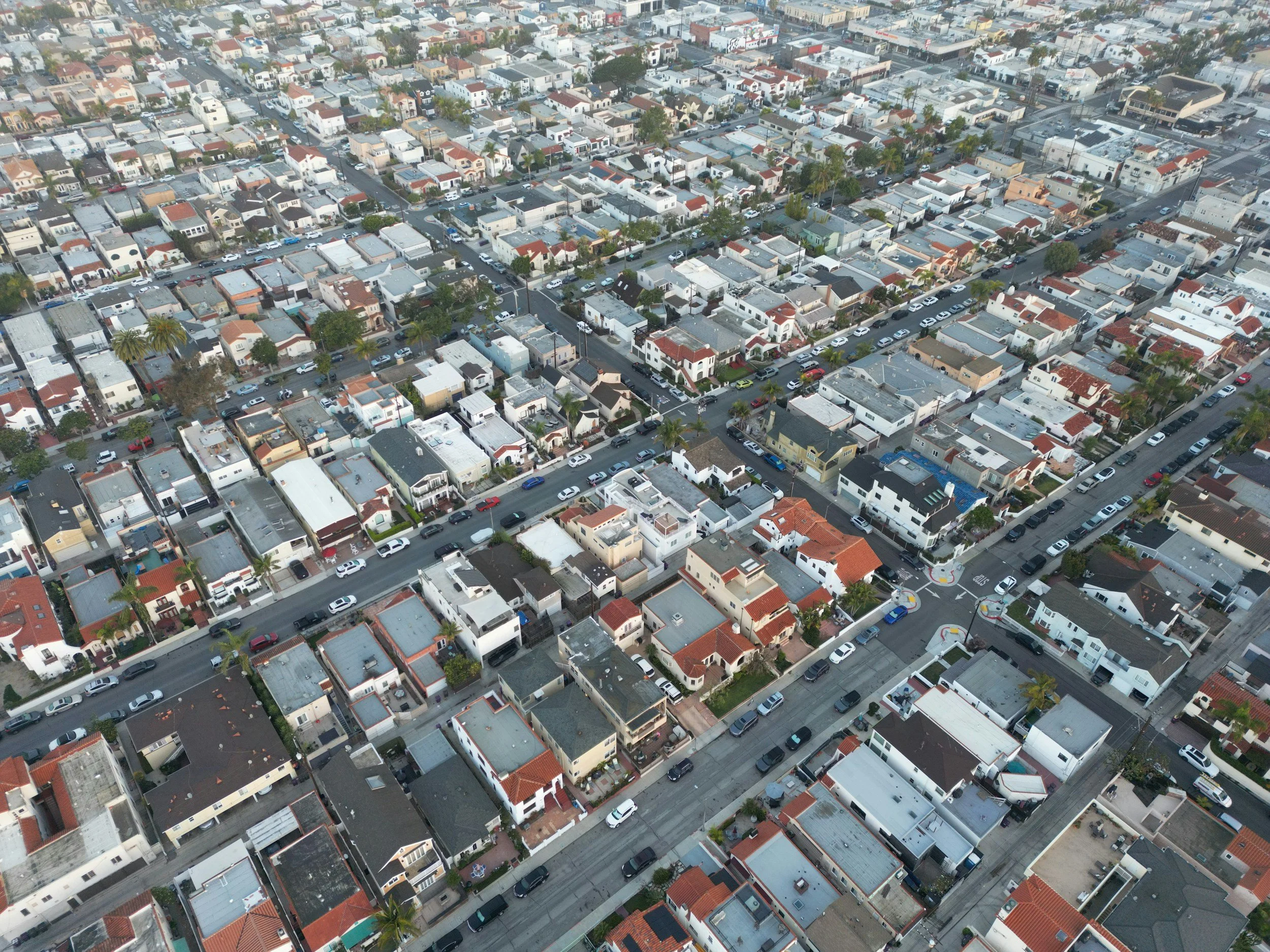 Aerial view of a densely packed residential neighborhood with houses, streets, and parked cars.