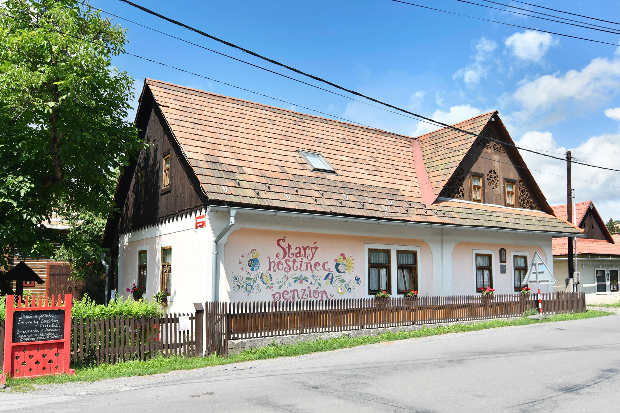 Osoba nalieva biele víno do pohára vonku na terase, v pozadí je nápis „PAUZA“.