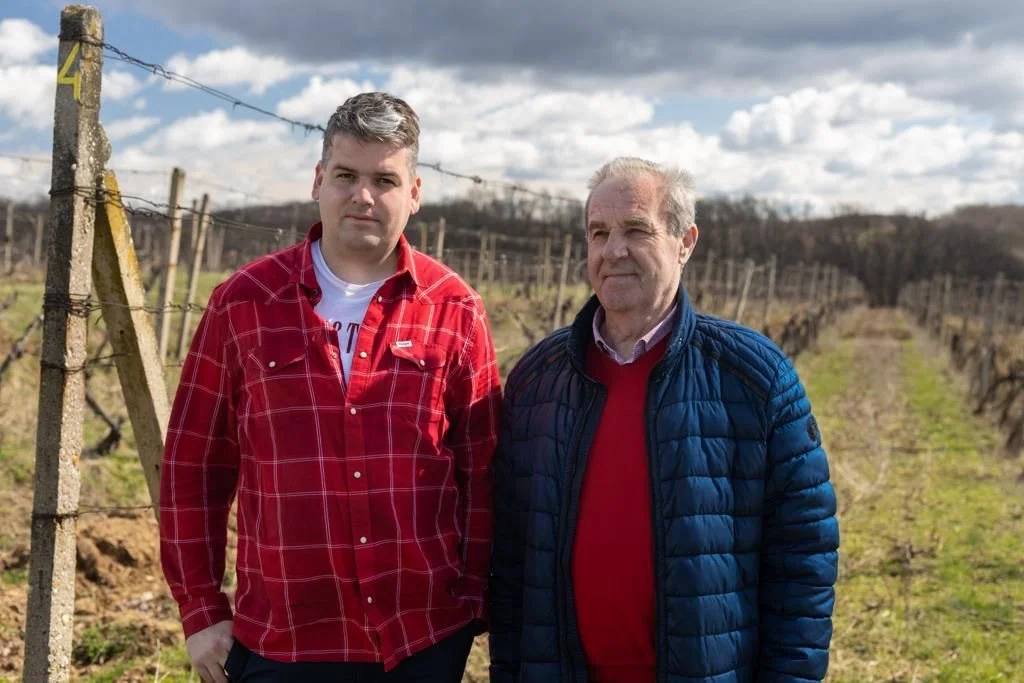 Dvaja muži stojací vo vinici s radmi viniča v pozadí, pod zamračenou oblohou. Jaroslav Knápek, Jaroslav Šuchma, Vinárstvo J&J Knápek, Vinojek, Rodinné Vinárstvo