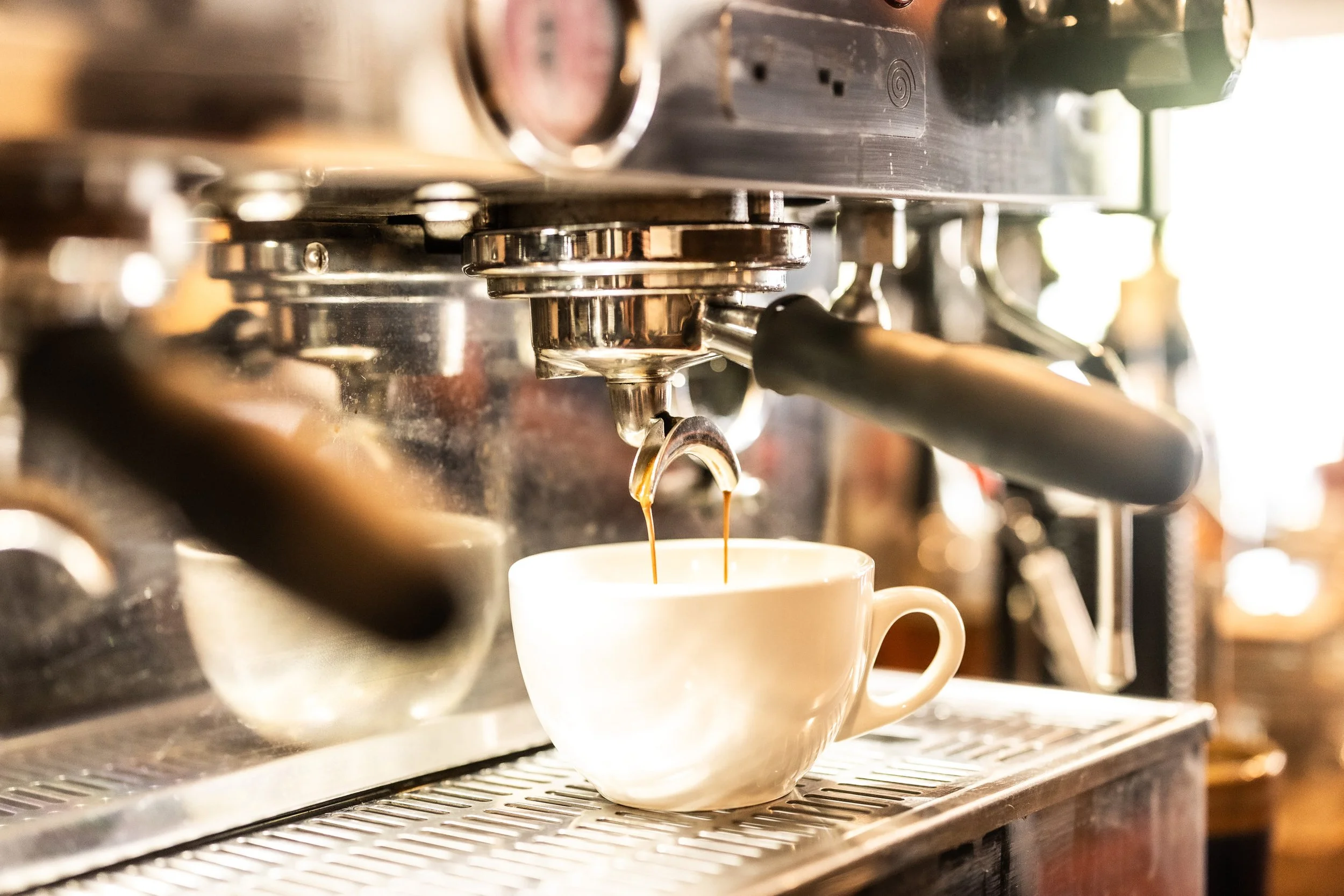 Espresso machine brewing coffee into a white ceramic cup.