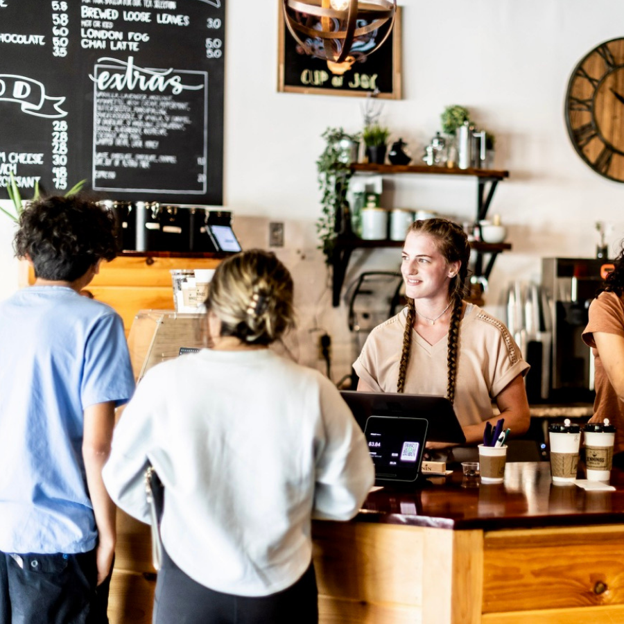 People ordering drinks at a coffee shop counter.