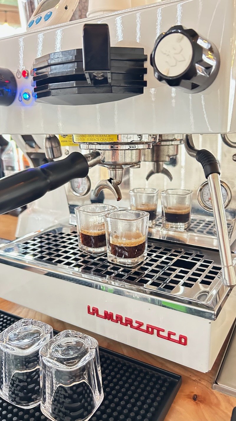 A La Marzocco espresso machine with three cups of freshly brewed espresso underneath, ready to serve.