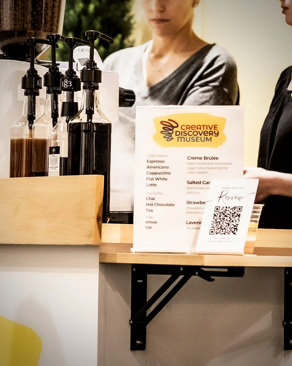 Custom branded coffee menu and syrup selection at The Coffee Cart's Creative Discovery Museum event.