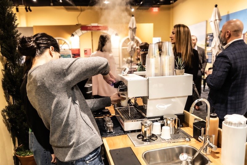 Barista preparing coffee at a an event from a mobile coffee cart with people waiting in line.