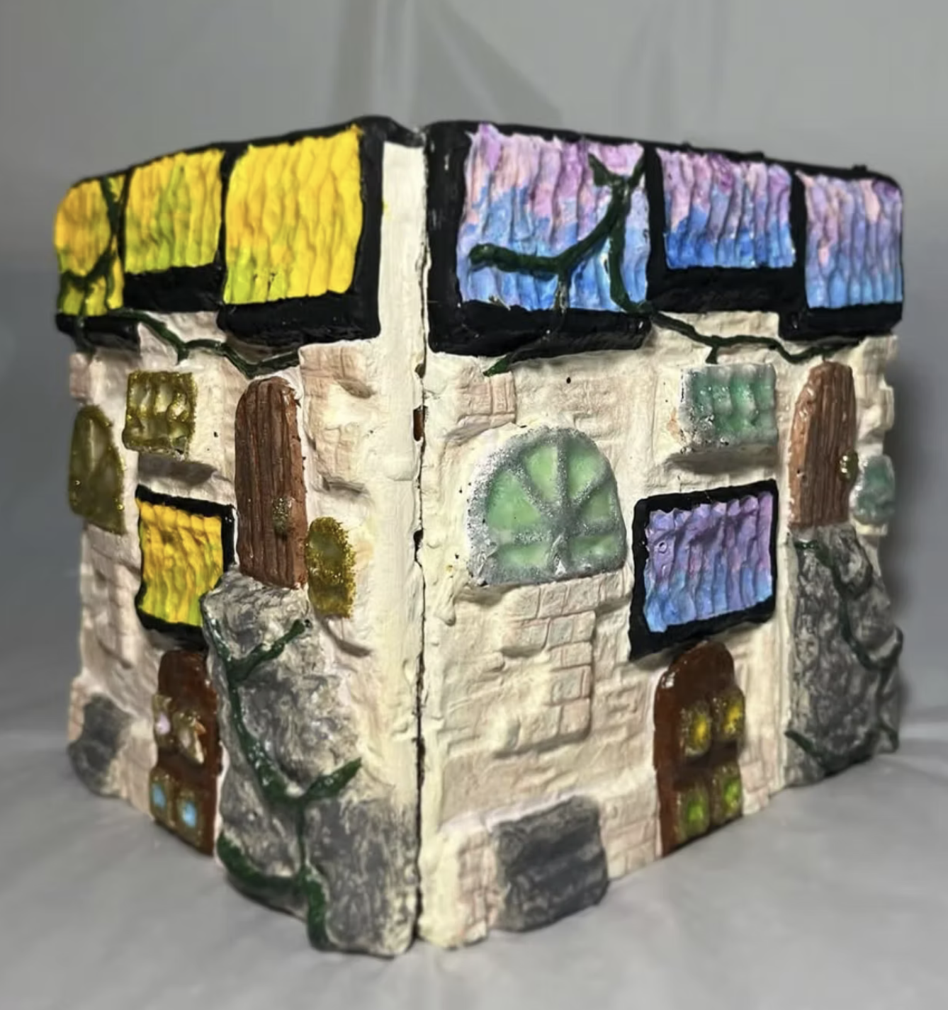 Sight specific wax relief sculpture - Starting out by creating a  relief sculpture from oil based clay, we then made molds of our pieces, filling them with wax, and painting the wax to create this final project. Mine represents a little fairy house t