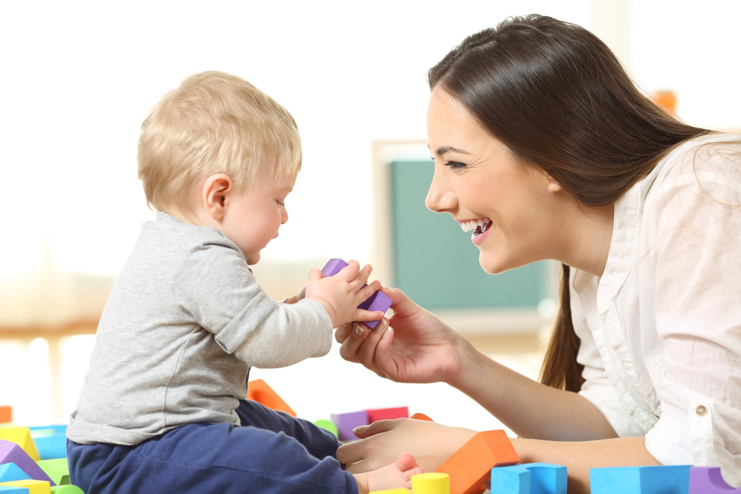 SLP  and infant playing on the floor to increase vocabulary for a late talker during child-led speech session in Laguna Hills